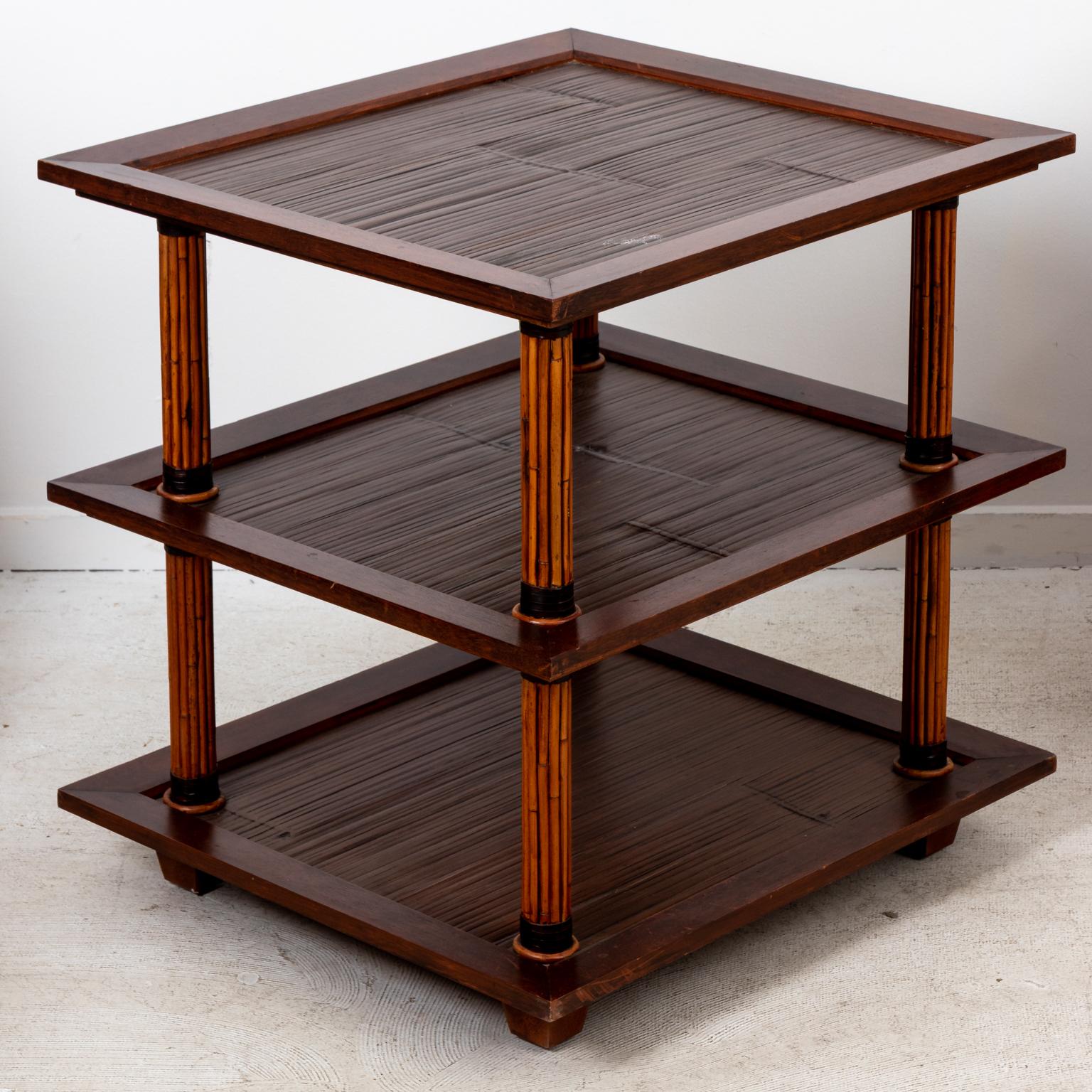 Circa 1980s pair of two tier side tables in the Palm Beach Regency style with bamboo columns and surfaces with Mahogany edges. The tables also features leather wrapped detail around the columns. Made in the Philippines. Please note of wear
