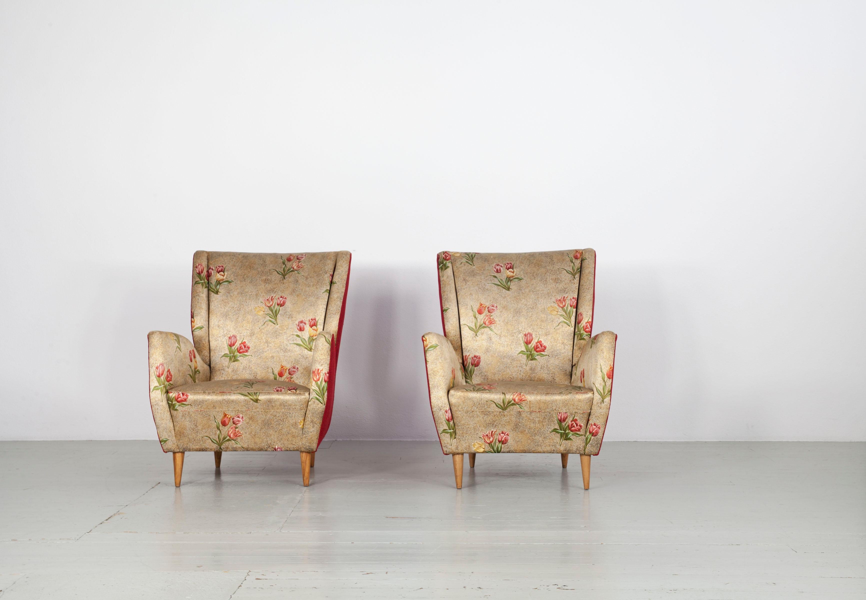 Italienisches Sesselpaar aus den 1950er Jahren mit konischen Holzbeinen und originalen Stoffbezügen. Die Stühle sind in gutem, authentischem Vintage-Zustand. Der Schaumstoff ist nur ein wenig durchgescheuert.