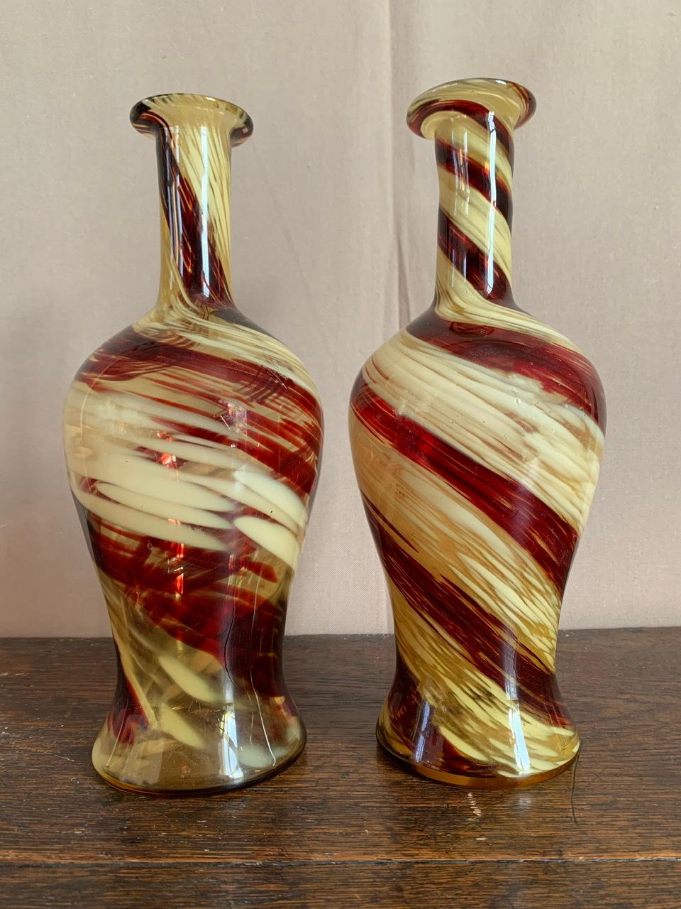 Charming pair of bottle vases in the taste of Murano production. They are both translucent and have a red and white spiral pattern. Because of their bottle shape they can also be used as a carafe.