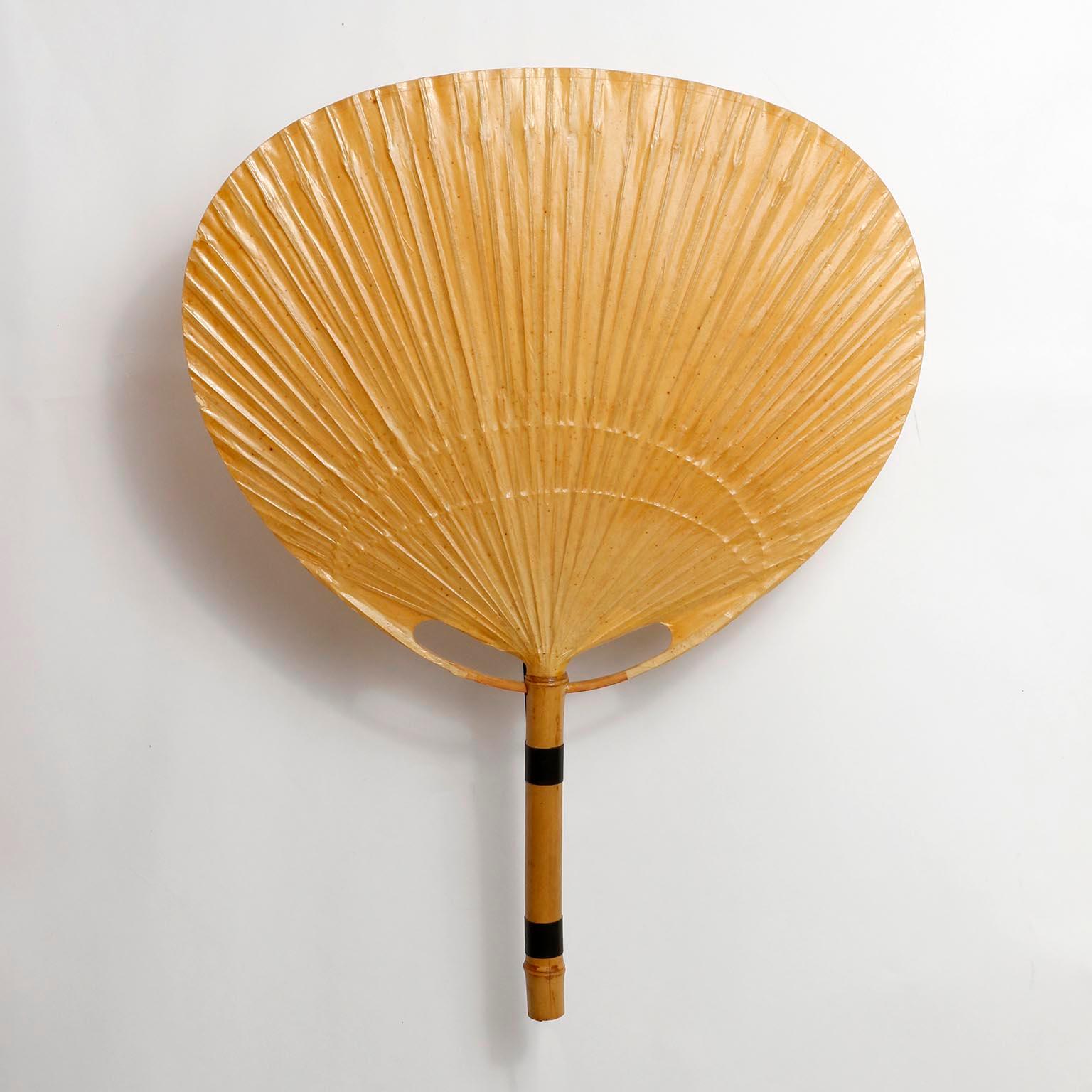 A pair of ‘Uchiwa’ wall light fixtures with large rice paper palm shaped leaves connected to a bamboo shaft by Ingo Maurer, Germany, 1970s.
This lamp was handmade of bamboo and Japanese rice paper in 1977.
Ingo Maurer’s interest in paper for