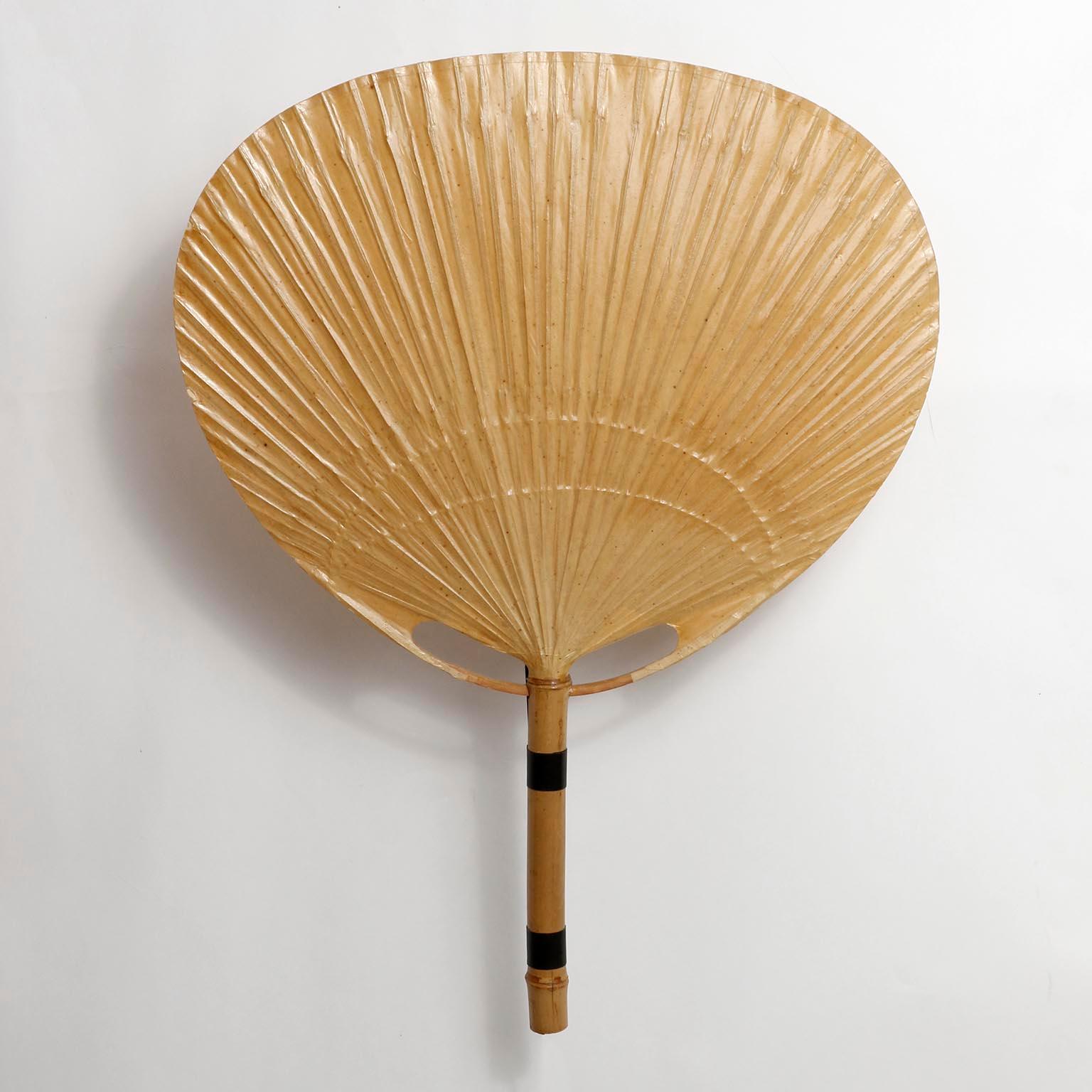 A pair of ‘Uchiwa’ wall light fixtures with large rice paper palm shaped leaves connected to a bamboo shaft by Ingo Maurer, Germany, 1970s.
This lamp was handmade of bamboo and Japanese rice paper in 1977.
Ingo Maurer’s interest in paper for