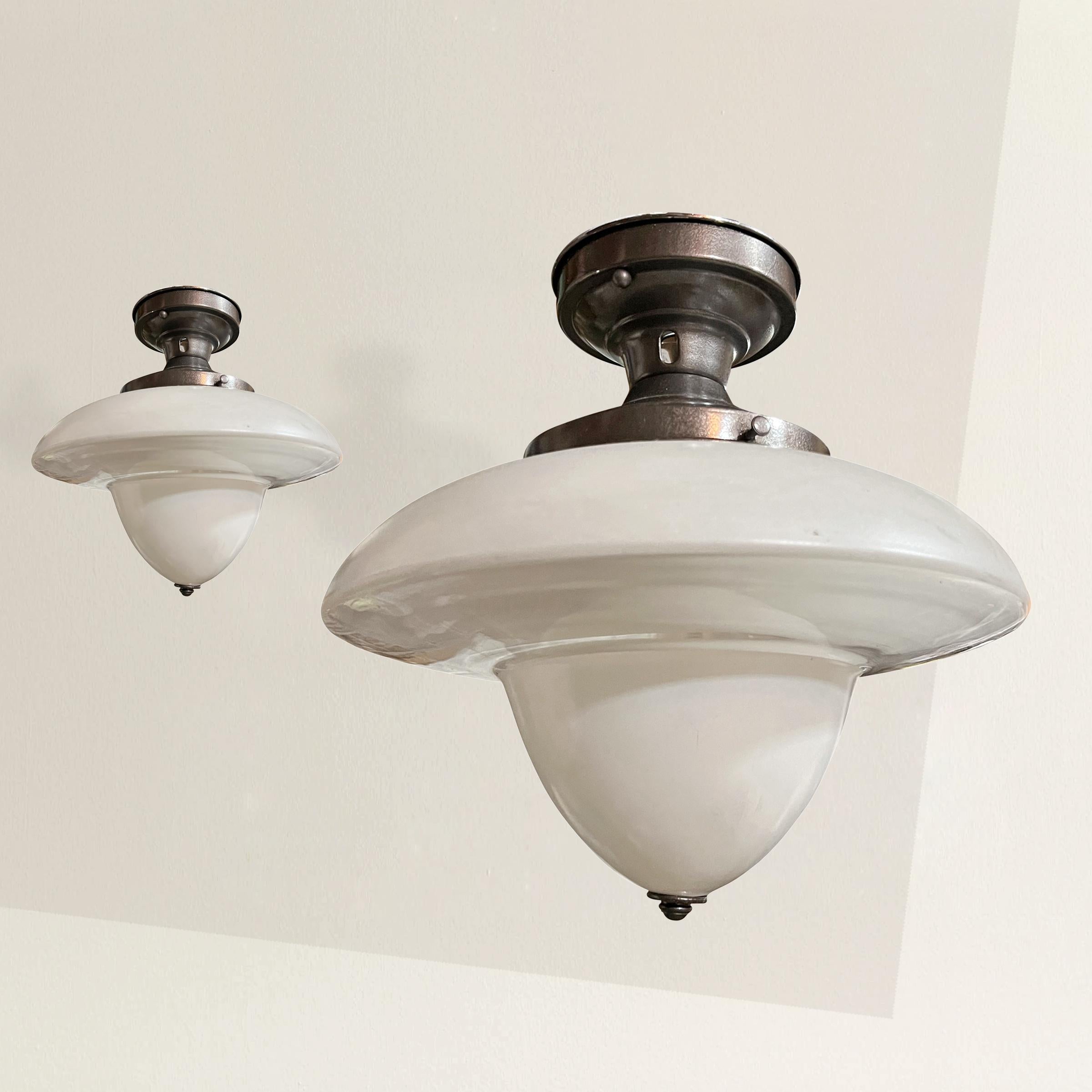 A stunning pair of unique early 20th century American schoolhouse fixtures with clear and opaque glass shades. The tops and conical sections are opaque and the undersides are clear. Perfect for your butler's pantry, kitchen, or down a hallway. Newly