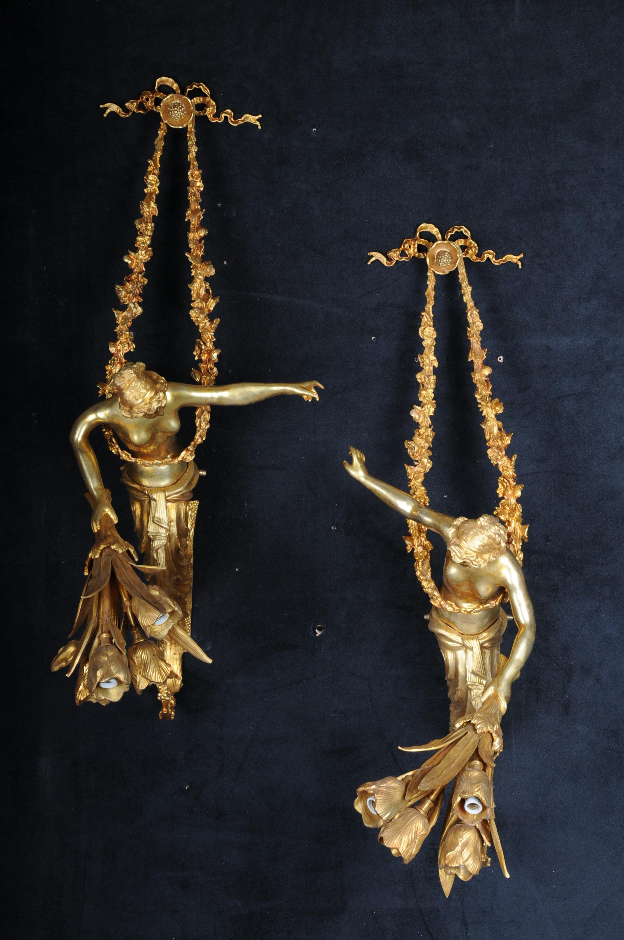 Pair of unique French sconces, gilt bronze, Paris

Solid bronze/brass, finely chased and gilded. Extremely decorative wall sconces, each with 4 sockets, electrified.

Floral garlands surround a nymph who is facing each other. The base and