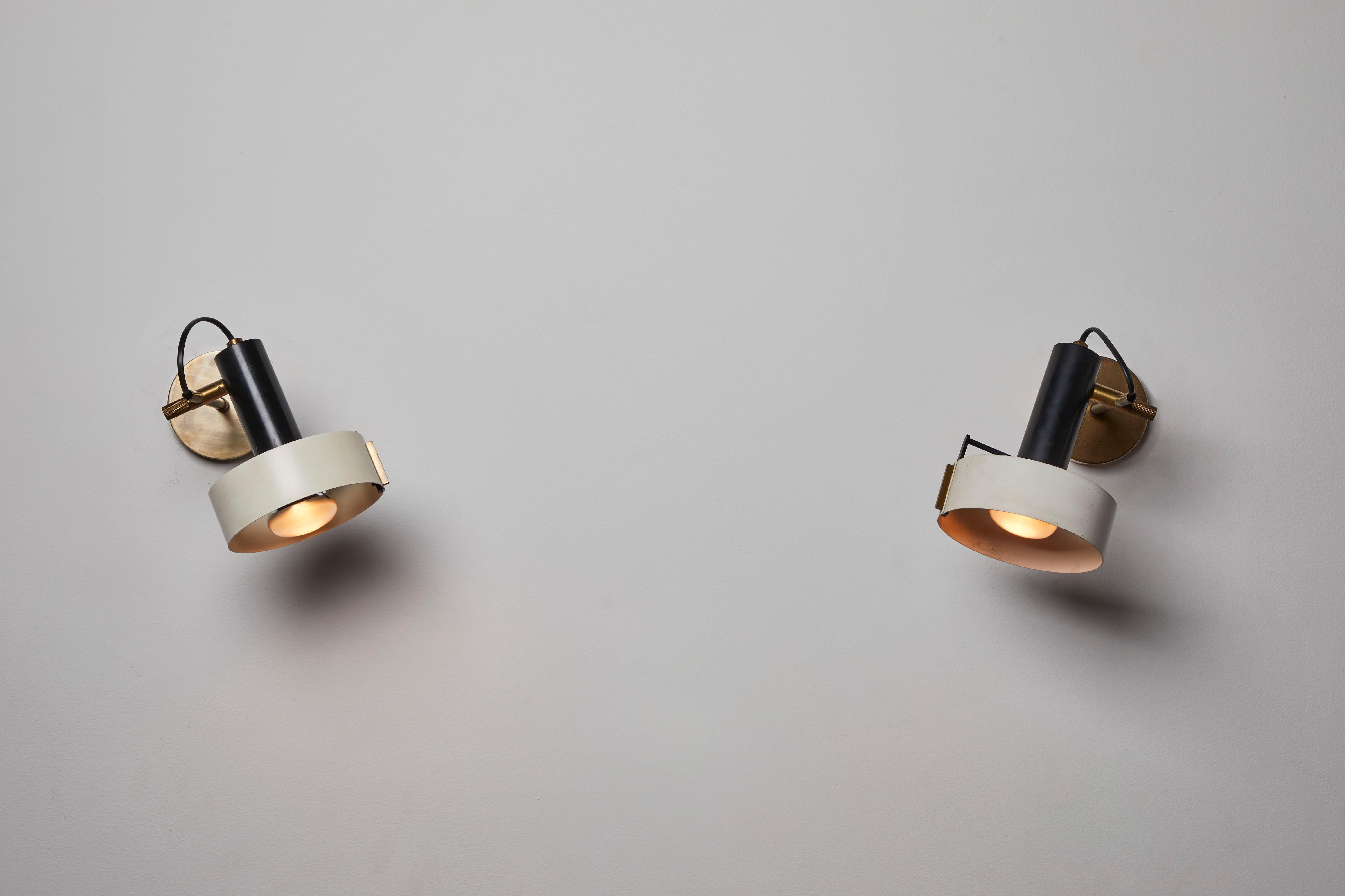 Pair of unique sconces by Stilnovo. Manufactured in Italy, circa 1960s. Enameled metal, brass. Rewired for U.S. junction boxes. Sconces adjust to various positions. Custom brass backplates. Metal rod that connects the ring shade to the base differs