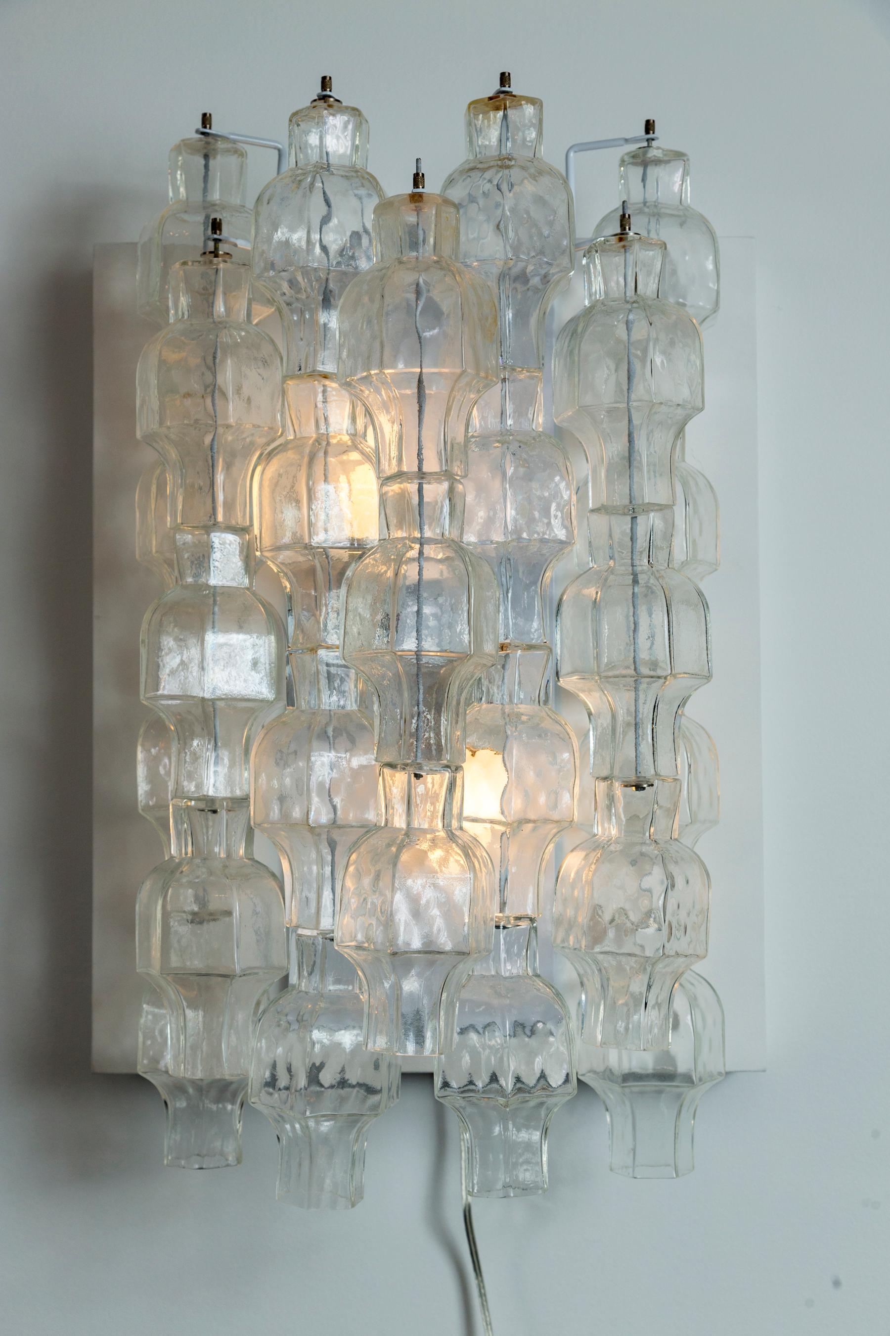This unique glass form is an unusual take from Venini’s polyhedri form originating from the 1960’s

Each wall light is composed of seven tiers of cascading rounded polydhri glass grouped in three and fours.

This vintage glass is newly mounted