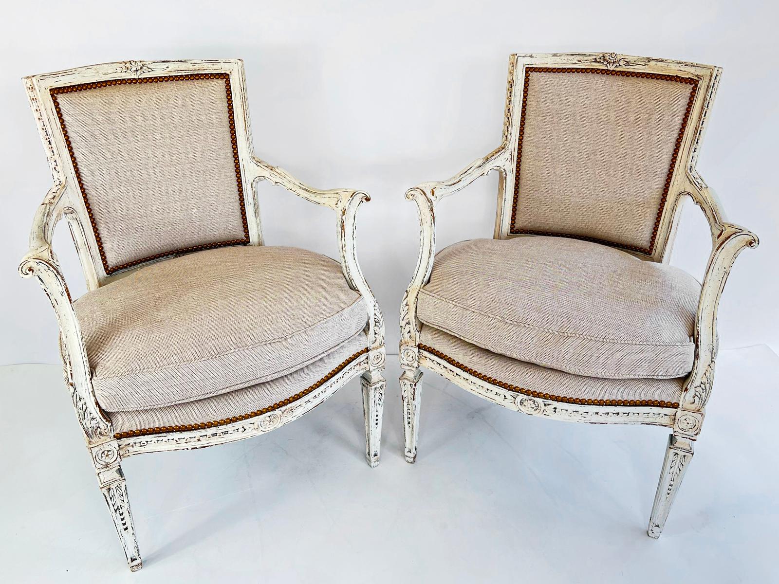 Pair of painted Italian armchairs. Each padded backrest is surrounded by a fielded frame surmounted by floral carving and decorated by beading along its side channel of the back. The outswept arms are uniquely carved with curvaceous scrolls, and