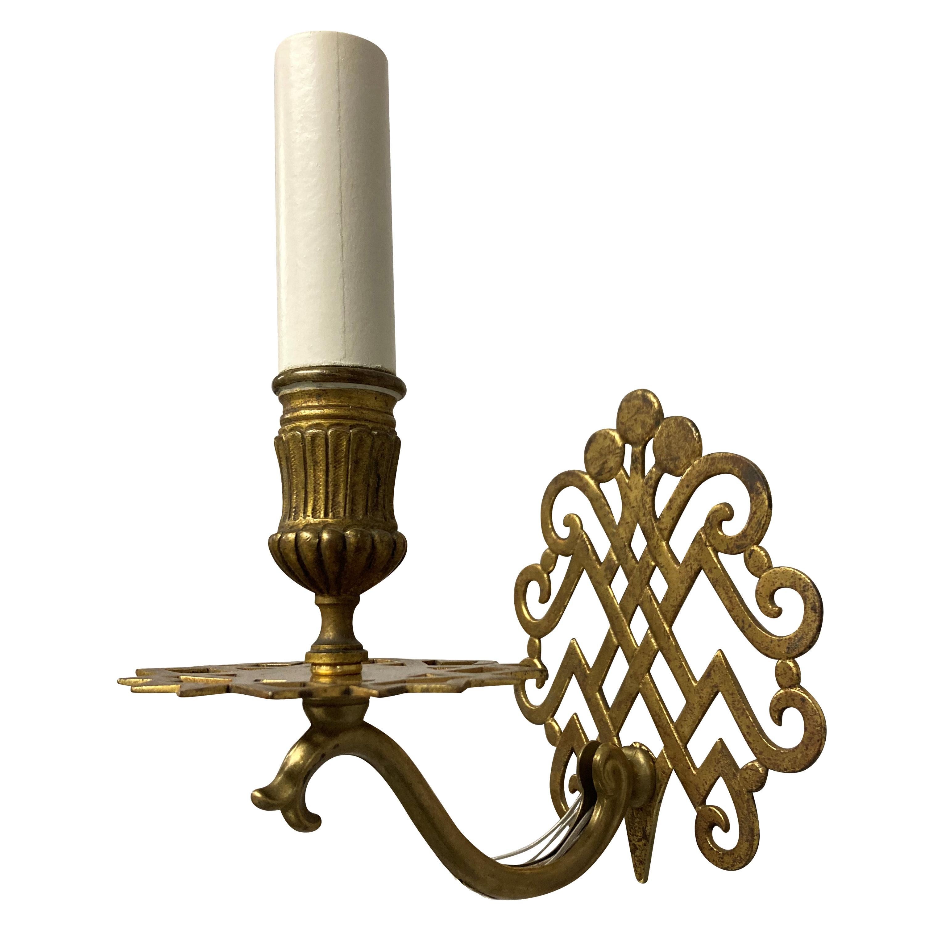 A pair of French single arm sconces of unusual design. with fret-work back plates and drip pans, supporting a single fitting.