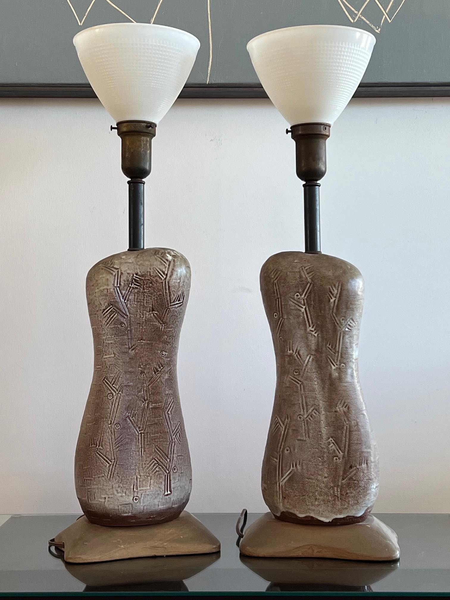 A pair of unusual ceramic lamps by Design Technics. Interesting biomorphic shapes with stylized decoration. Original shades, note matching biomorphic shades.