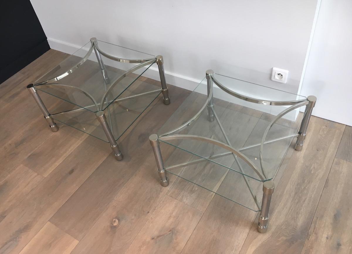 This pair of unusual side tables is made of chrome and glass. The bases have a nice curved shape with a stretcher. This is a French work, circa 1970.