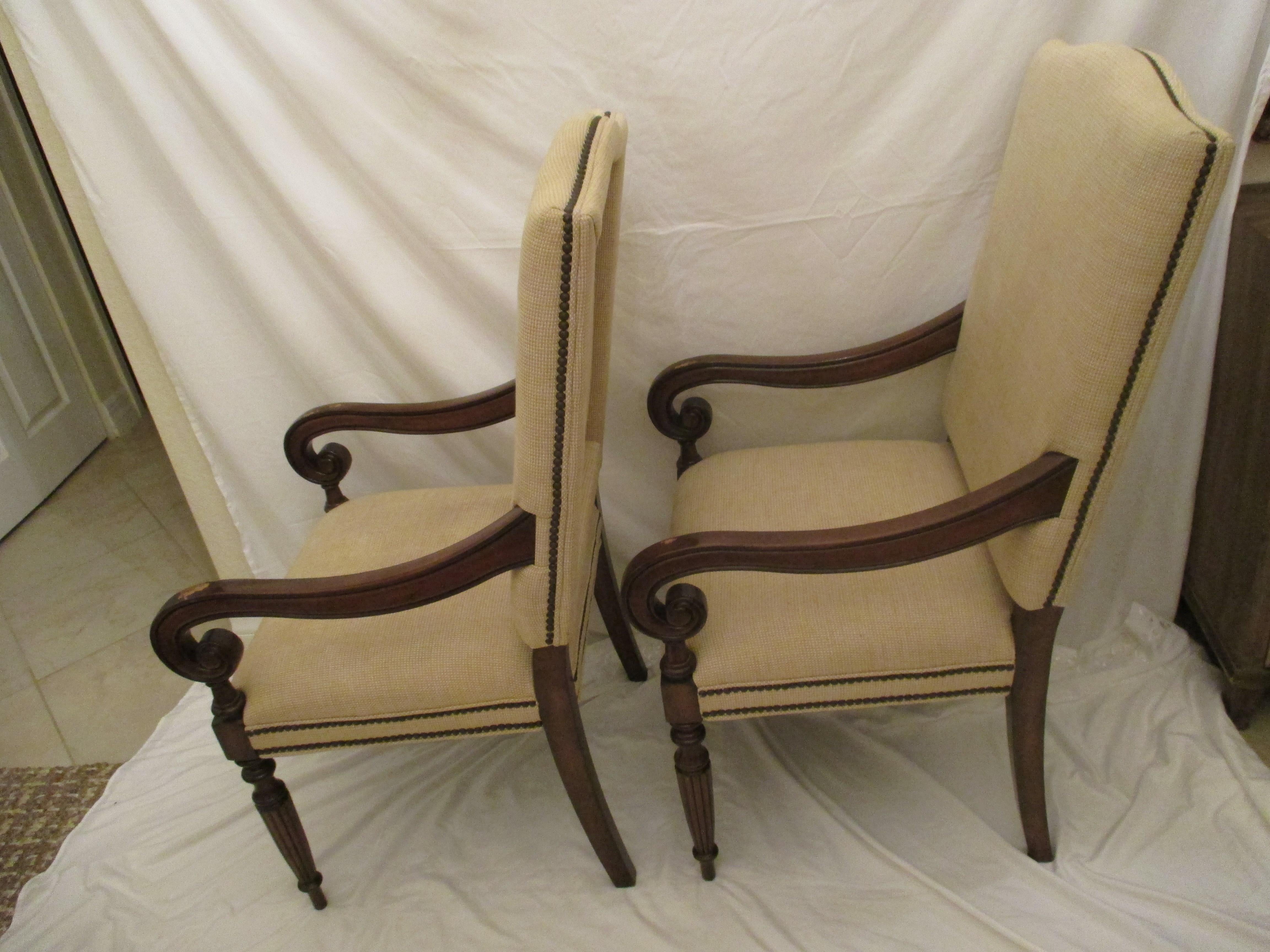 Pair of dark stained upholstered club chairs with original neutral upholstery in good condition. Chairs have nailhead trim and signs of wear on top of arms. Measurements are listed, however, floor to top of arm is 26.75.”