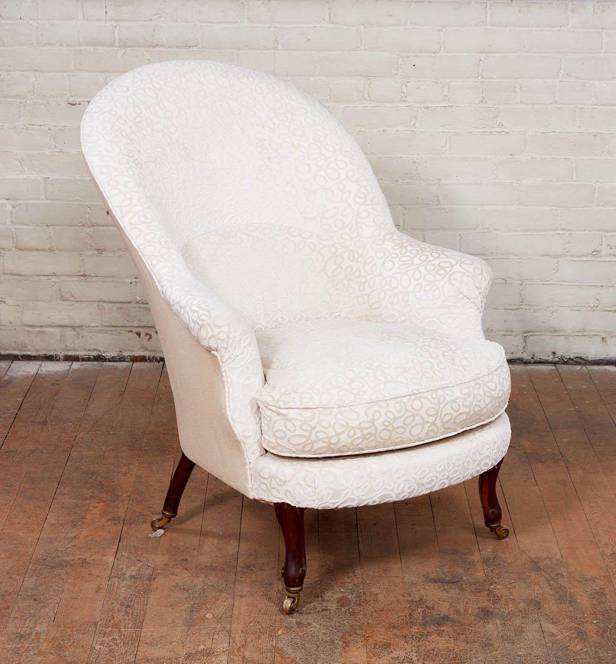 A pair of upholstered armchairs having raked slipper forms with arched backs incorporating lumbar padding, streamlined rolled arms and long stylish Art Nouveau carved outswept legs ending in brass castors. Upholstered in a high quality cut silk