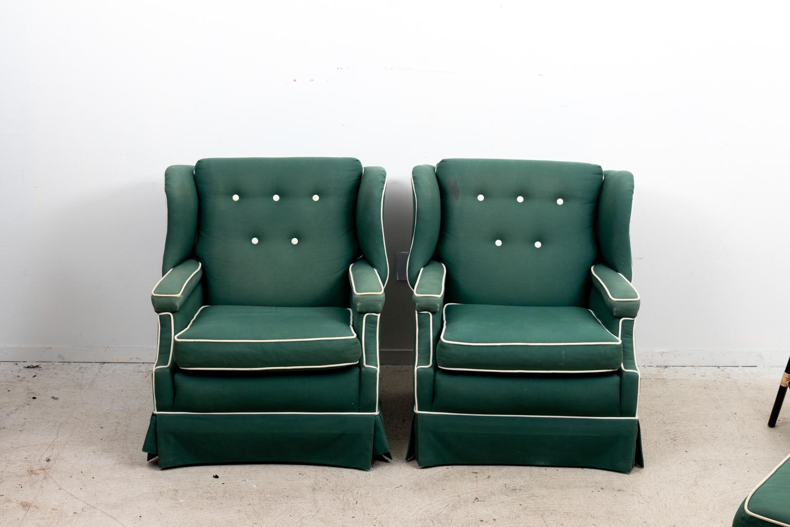 Pair of upholstered wingback club chairs with matching ottoman and white tufted button seat backs. The chairs also feature white chord accent trim. Please note of wear consistent with age.