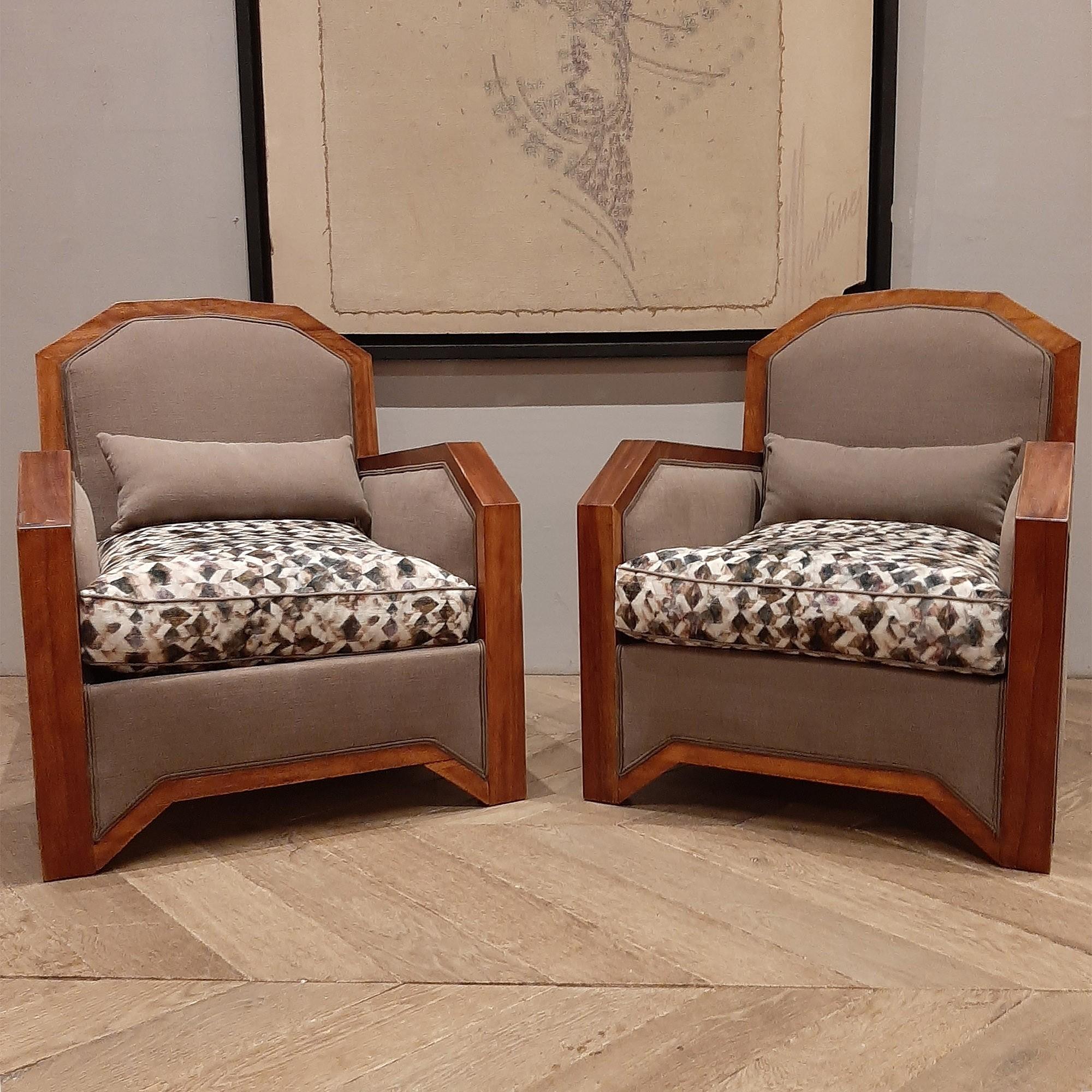 A pair of upholstered French Art Deco armchairs. With their angular shape in their outstanding mahogany wood frames and with the Art Deco inspired fabric, these chairs in the style of Emile-Jacques Ruhlmann are eye-catching reminders of a glamorous