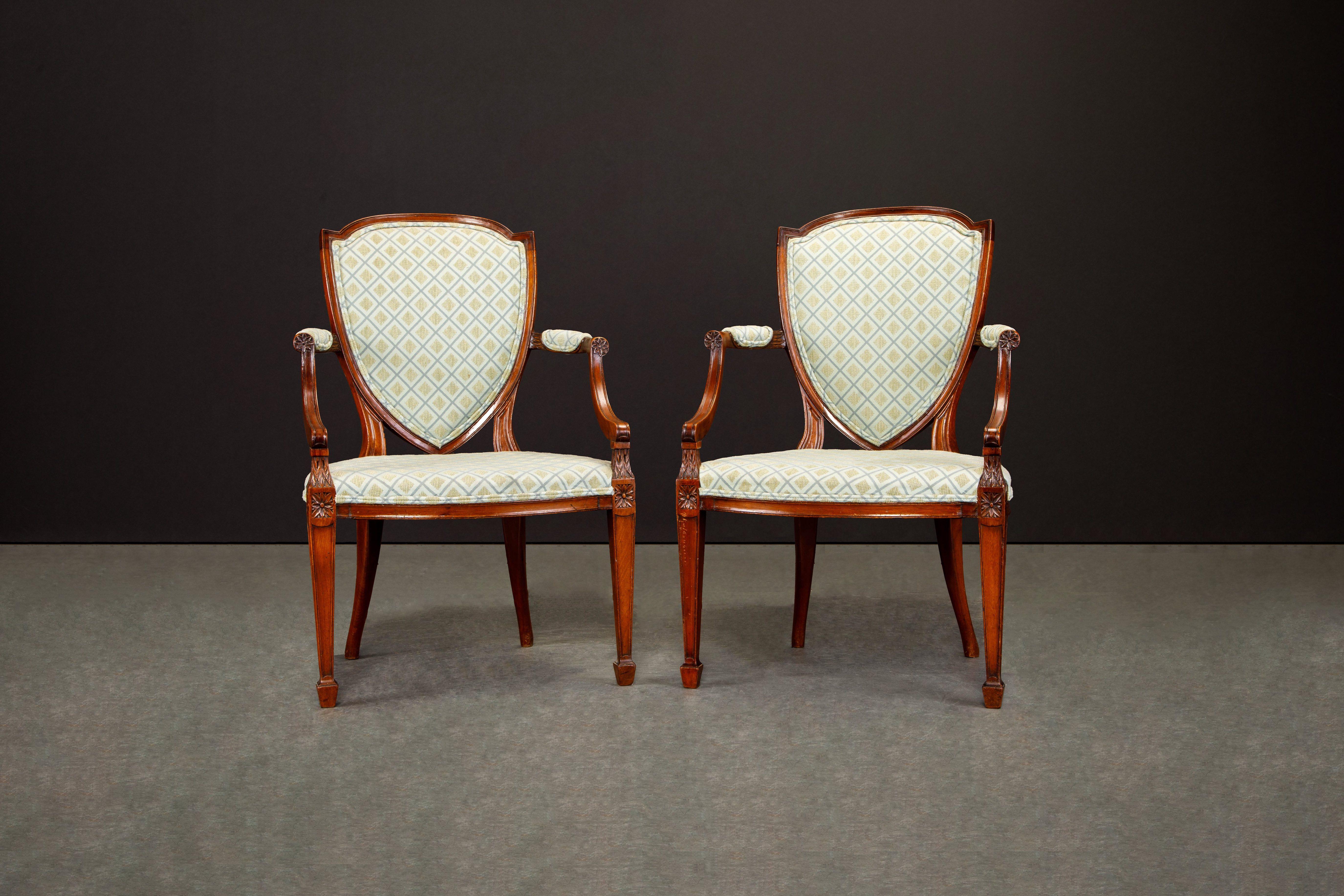 This exquisite pair of circa 1870s Hepplewhite style 'Shield-Back' armchairs are exquisite. We believe the wood to be crafted from solid Mahogany with intricate detailed carved details. 

The upholstered back and arms provide additional comfort
