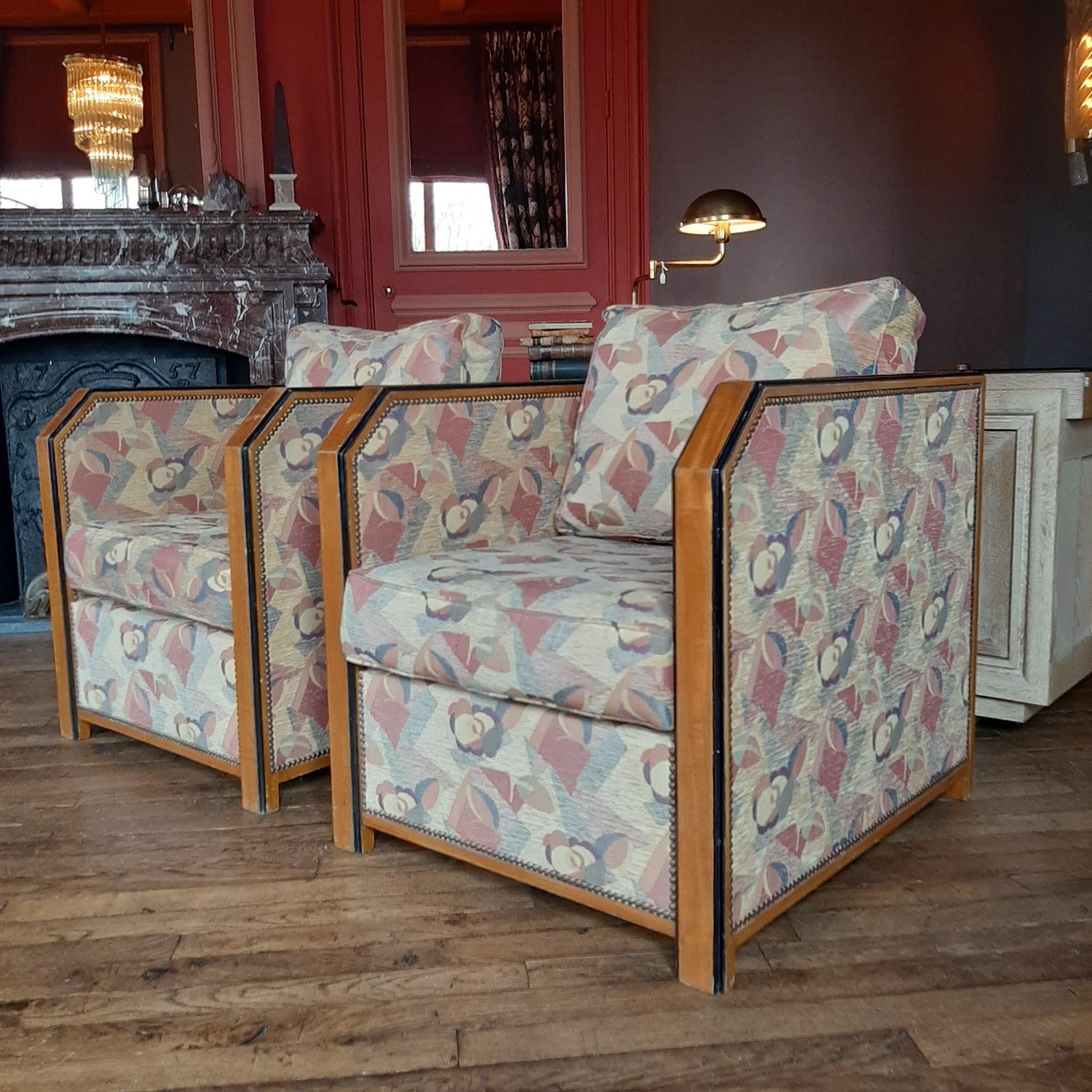 A pair of upholstered large French Art Deco club chairs. With their angular look and newly upholstered Art Deco inspired fabric, these arm chairs inspired by the style of Emile-Jacques Ruhlmann are stunning eye catchers from the 1930s. Super