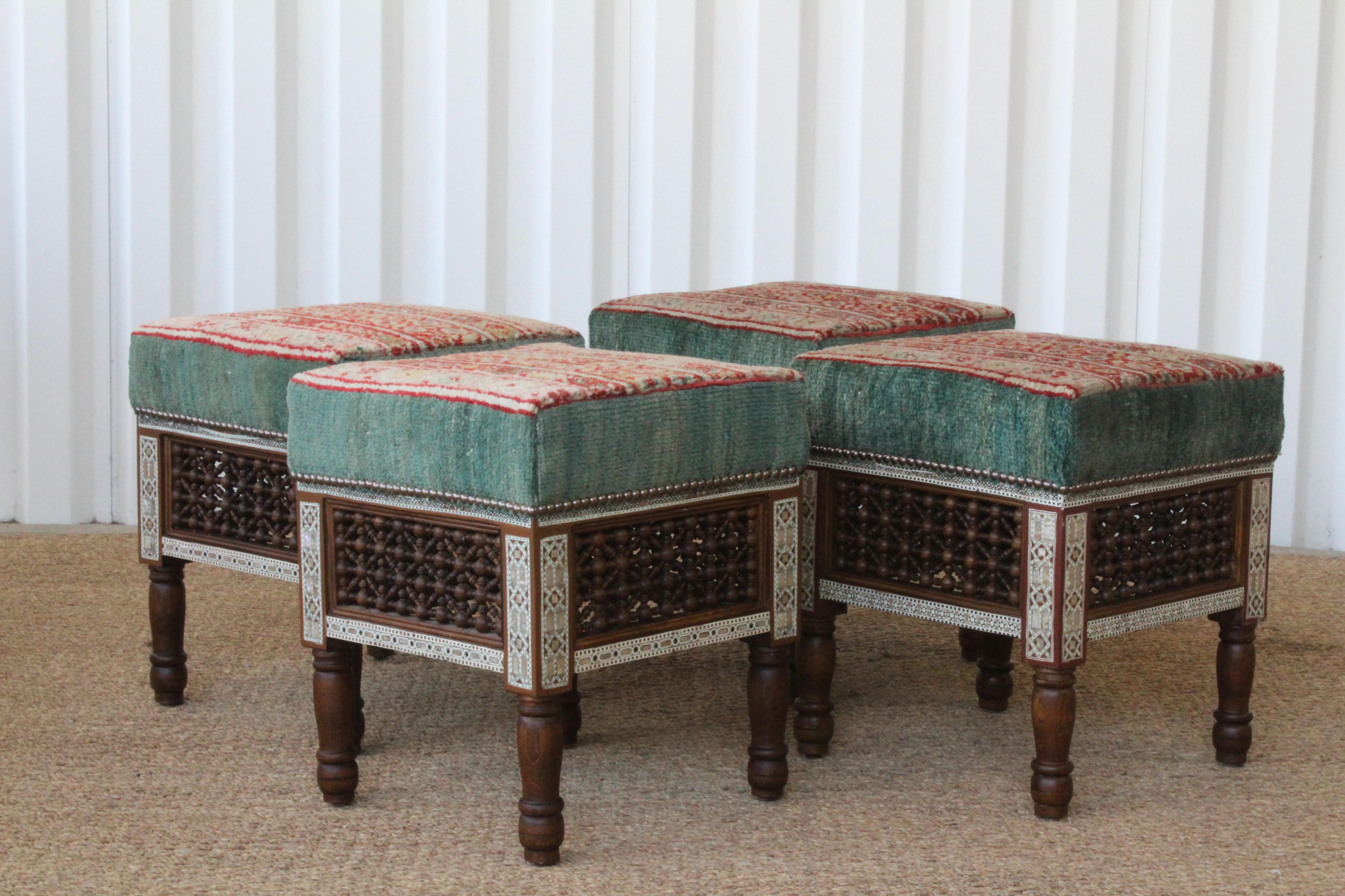 Pair of vintage Moorish stools upholstered in a vintage wool Turkish rug. They are in excellent condition. Made of walnut with carved details and bone and pearl inlay. Sold as a pair. Two pairs available.