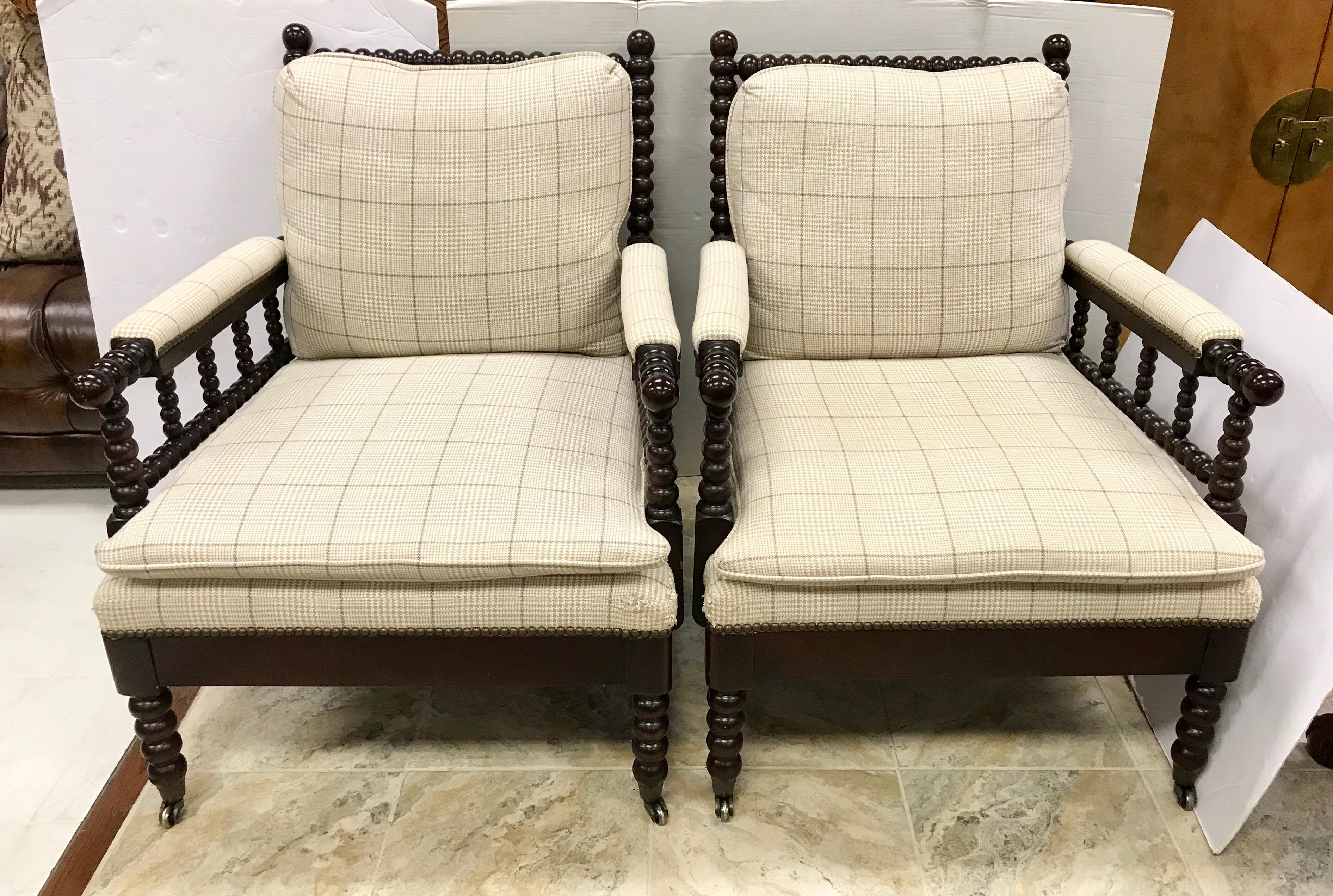 Pair of mahogany spool armchairs by Vanguard, circa 1990s. Upholstered in a neutral plaid and features
casters on front legs and nailheads throughout.