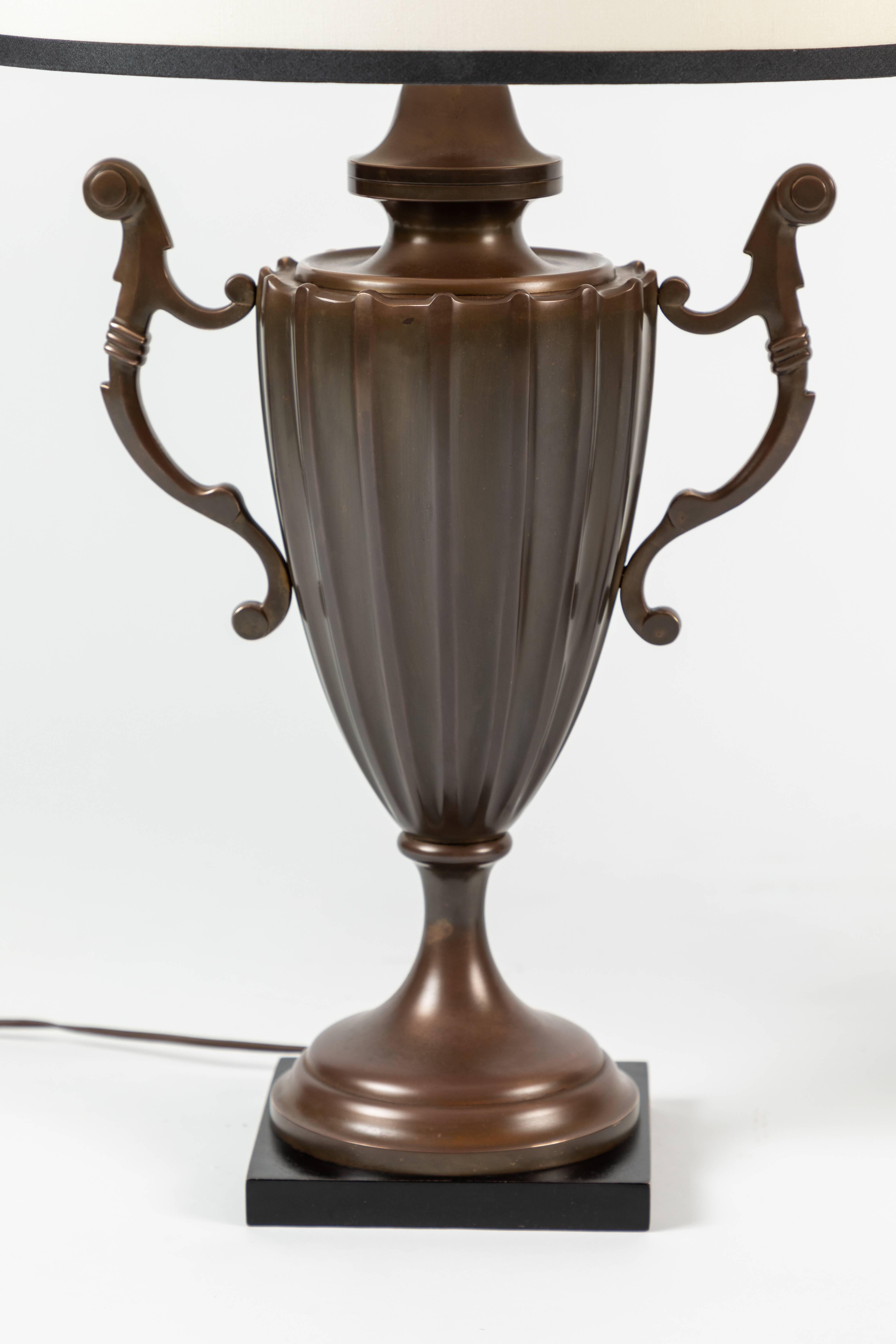 Manufactured by Chapman Manufacturing Company, these table lamps resembles a fluted English urn (or an Accolade cup trophy) made from solid brass. 

The shades are newly designed, and custom made.