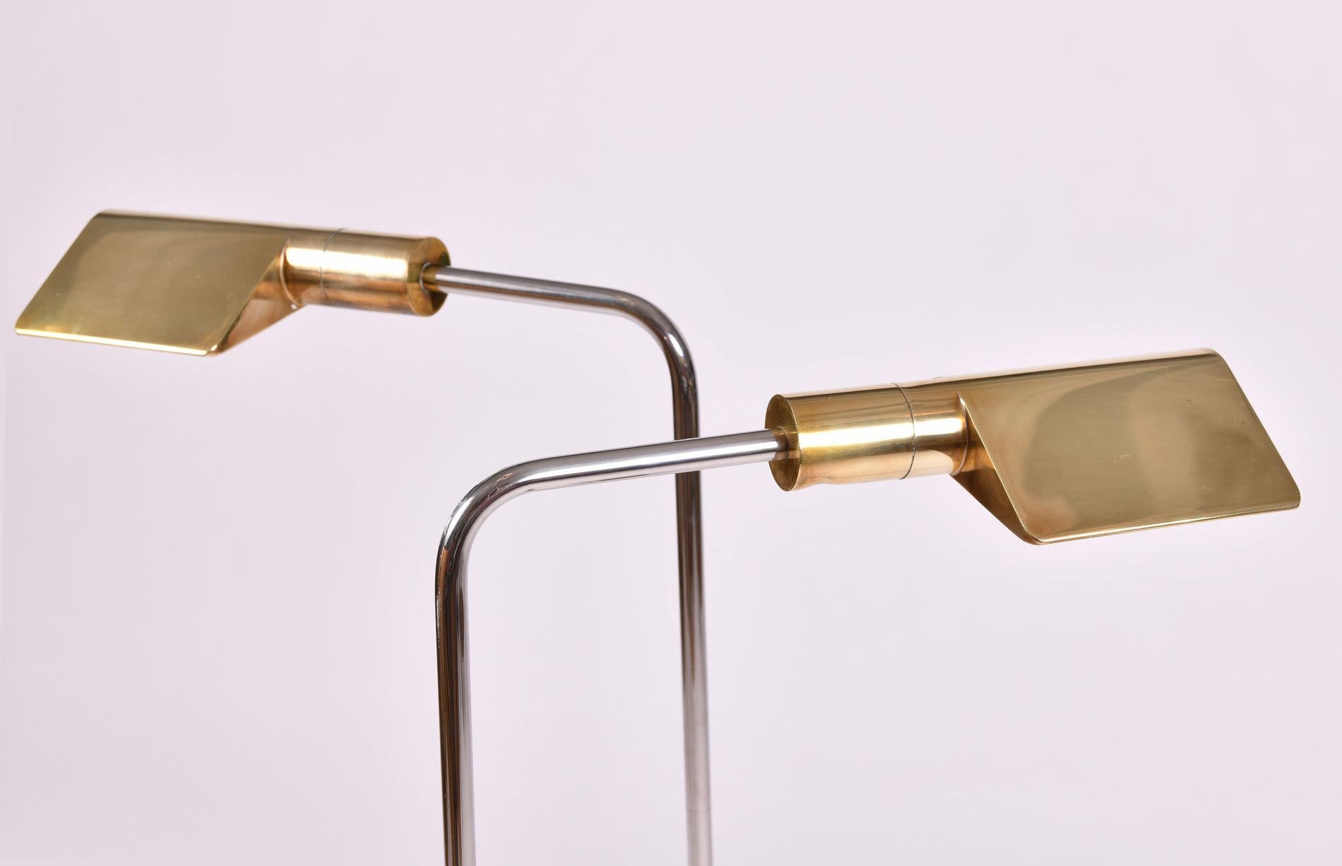 Sleek pair of floor lamps featuring a brass shade and base with polished chrome arm. Lamps are adjustable in height with swivel shades. Classic design by US designer Cedric Hartman, signed and stamped beneath base (see detailed image).