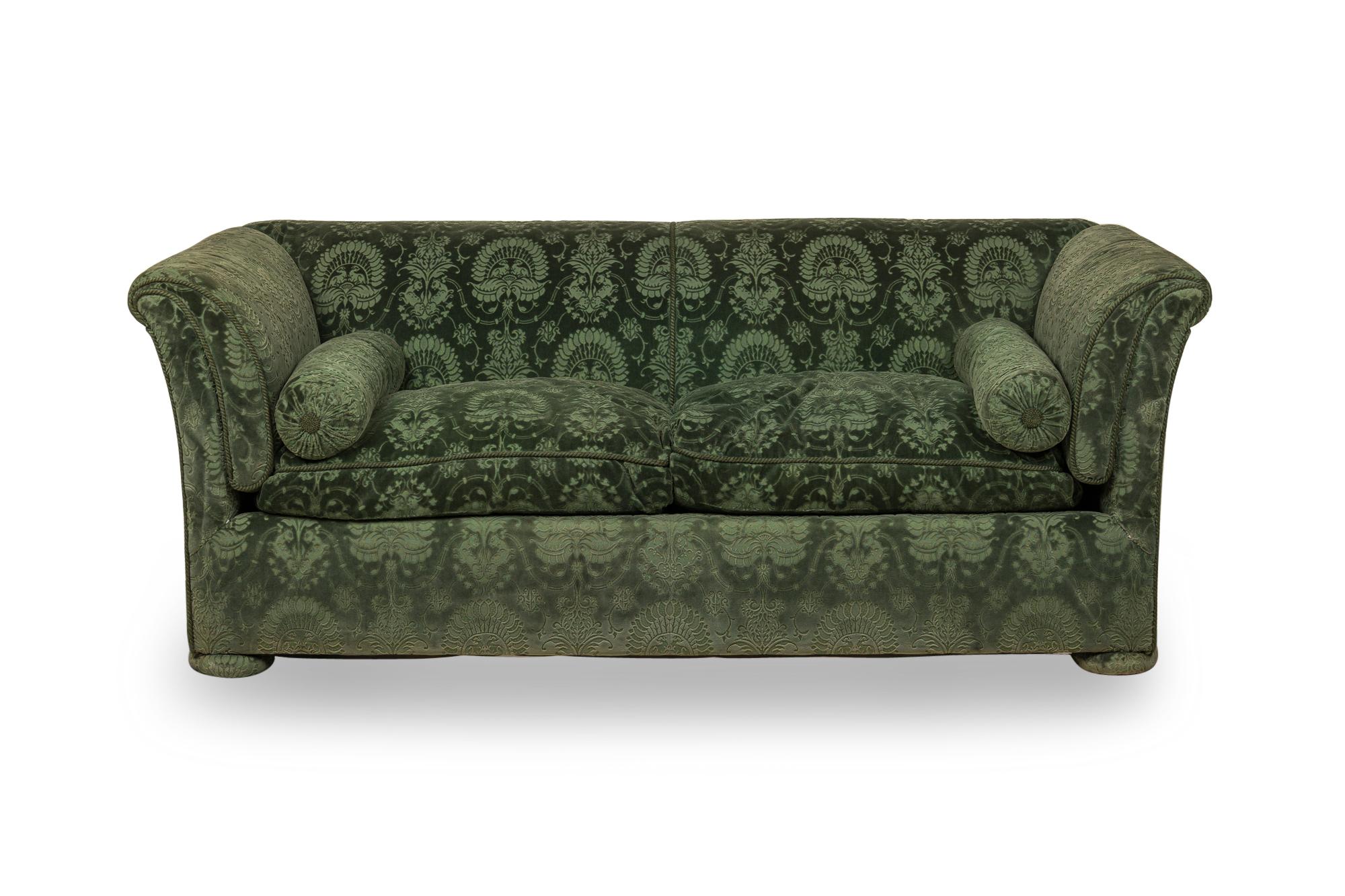 Pair of French Victorian style sofas with high backs and arms that flare gently outward, upholstered in a dark blue and green damask velvet with matching bolster pillows and removable seat cushions, resting on four upholstered bun feet.