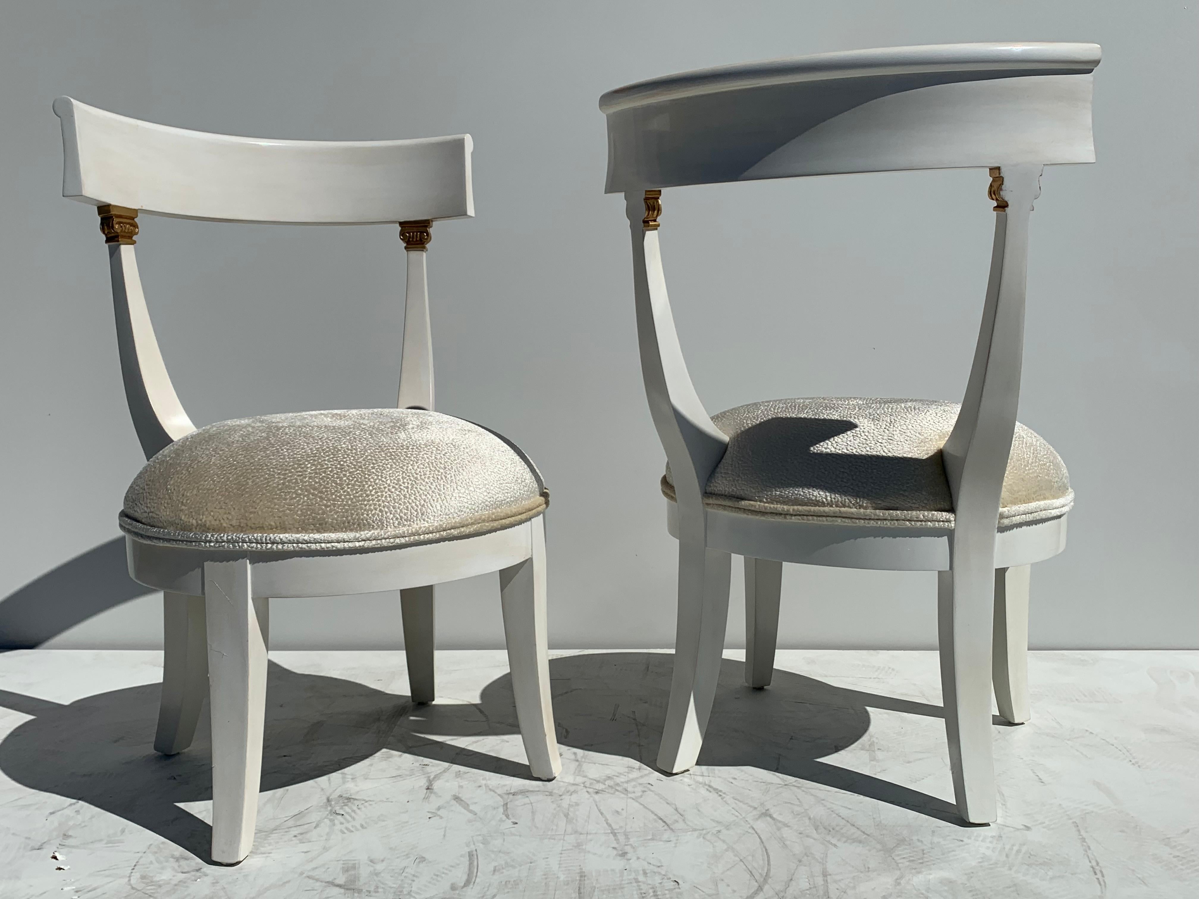 Pair of vanity slipper chairs is gold leaf detail.