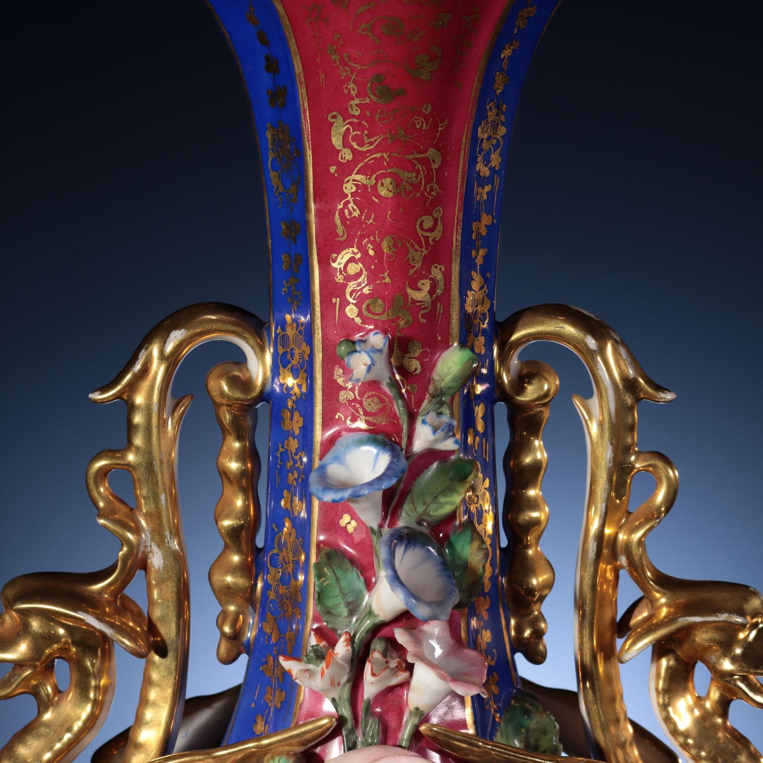 Pair of flask shaped vases with narrow neck and octagonal base. Two winged dragons make up the handles of the vases; there are two reserves inside a flower crown on the front, painted with elegant scenes of oriental taste, depicting Arabs in palm