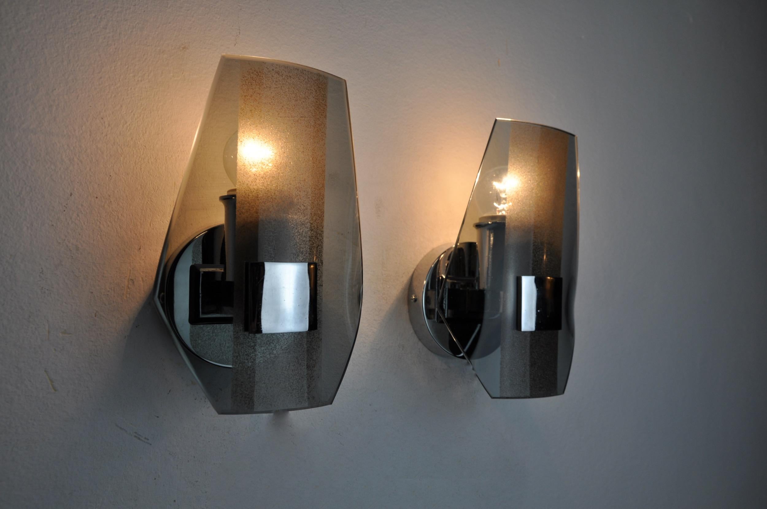 Very nice pair of veca wall lamps produced in italy in the 70s. Wall lamps composed of black cut glass plates and a chrome structure. Unique object that will illuminate wonderfully and bring a real design touch to your interior. Verified