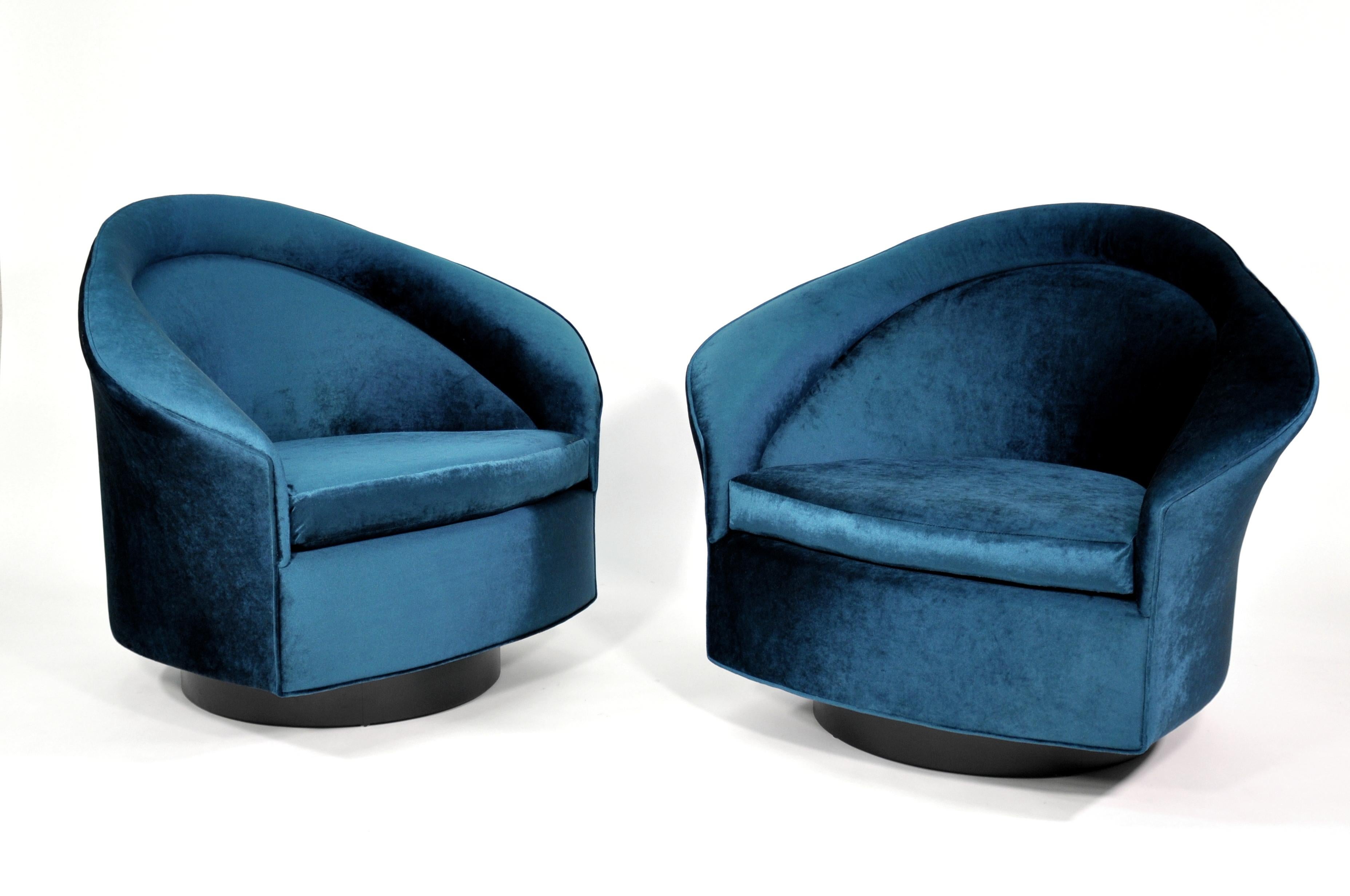 A stunning pair of Mid-Century Modern barrel back swiveling club chairs, designed by Adrian Pearsall for Craft Associates. Fully restored and upholstered in a luxurious blue jewel tone velvet, features an ebonized walnut base with swiveling and