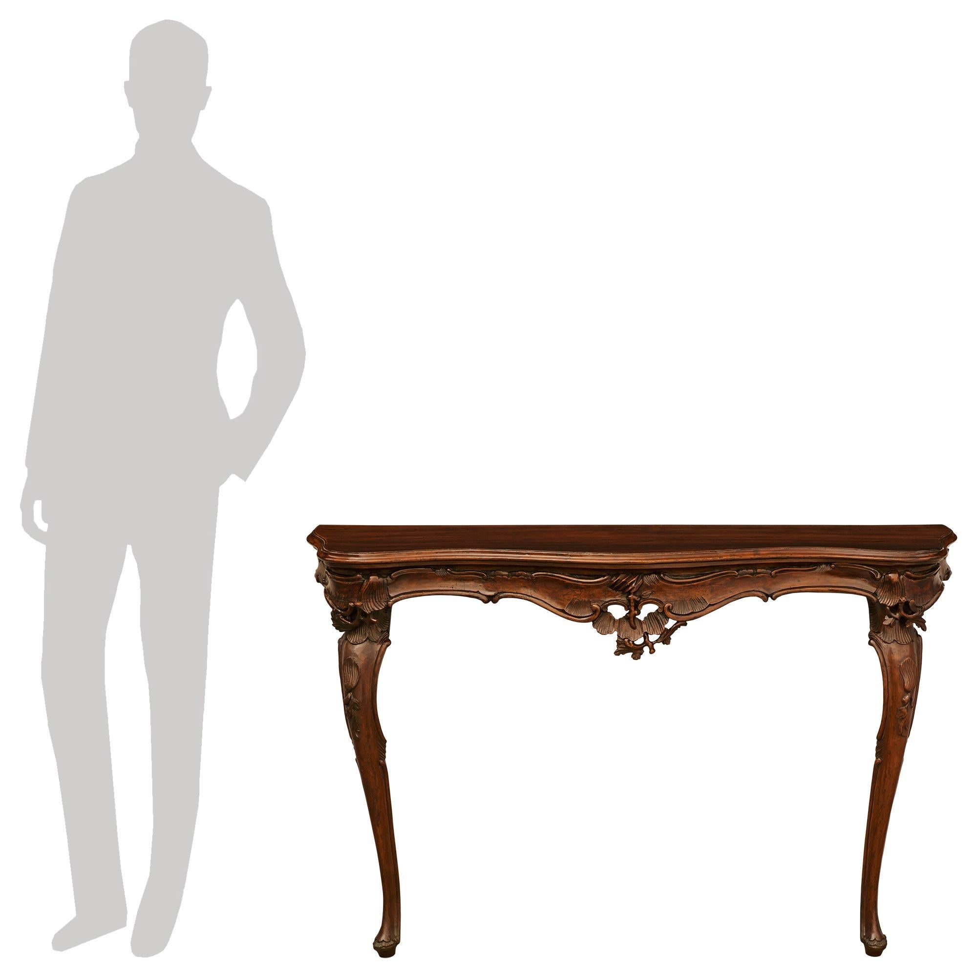 Ein atemberaubendes und äußerst dekoratives Paar venezianischer Konsolen aus Nussbaum im Stil Louis XV des 19. Jede der eleganten Konsolen steht auf schlanken Cabriole-Beinen mit schönen, verschnörkelten Blattwerkfüßen und reich geschnitzten
