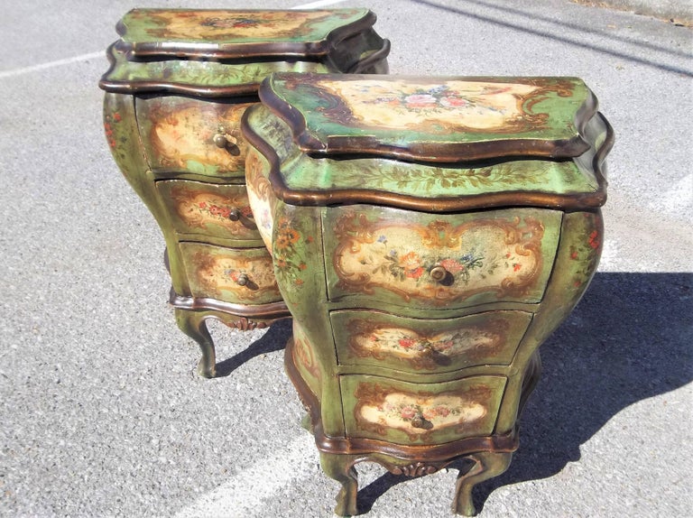 The commodini of bombe' form with painted scrolls and inset floral panels . Each with three drawers. Probably made with an intentional distress look and time has added more wear. The green ground changes hues with lighting.

Losses, wear and rubbing