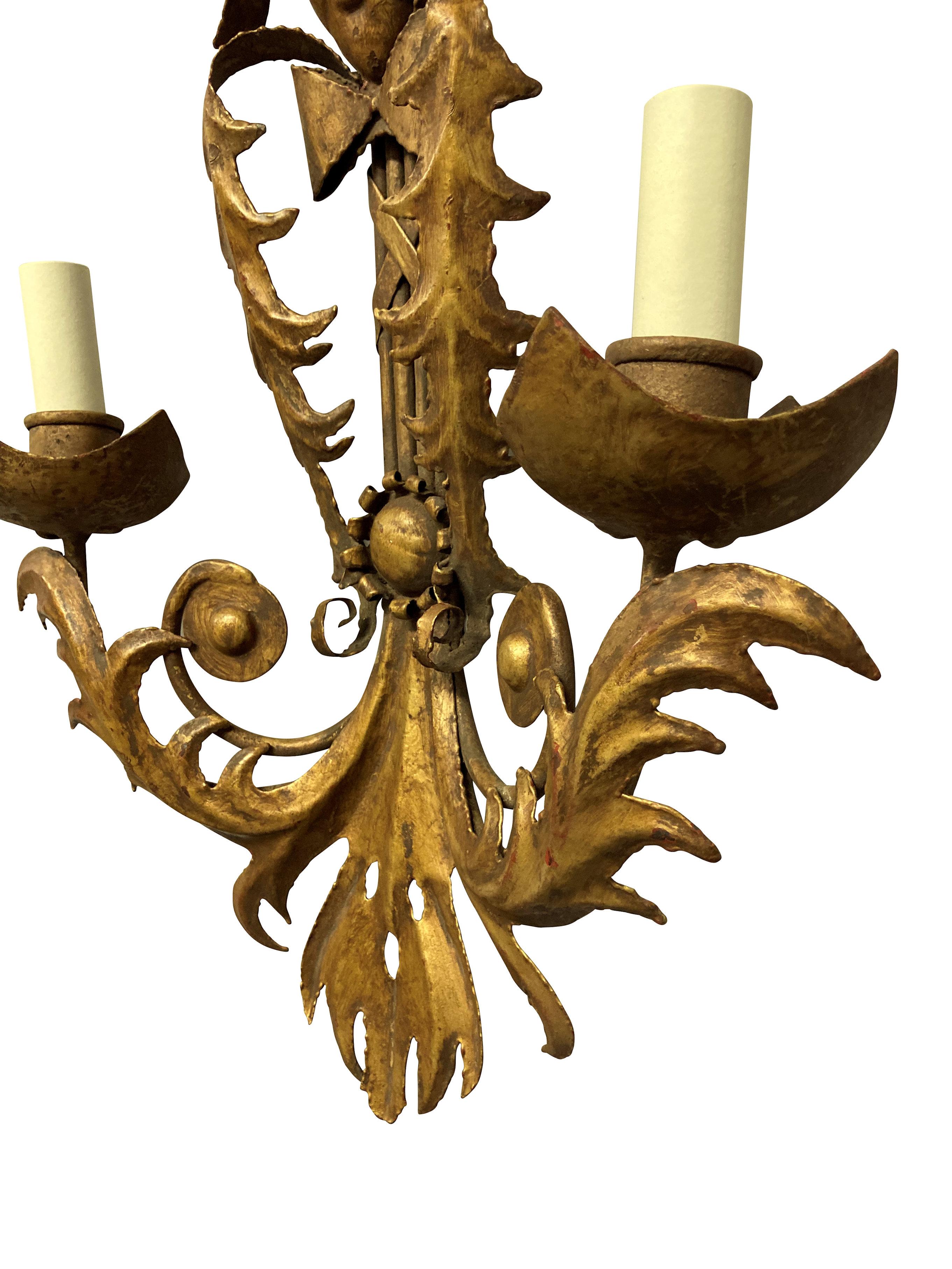 A pair of Venetian gilt metal wall lights, each with twin arms and depicting Venetian carnival masks.