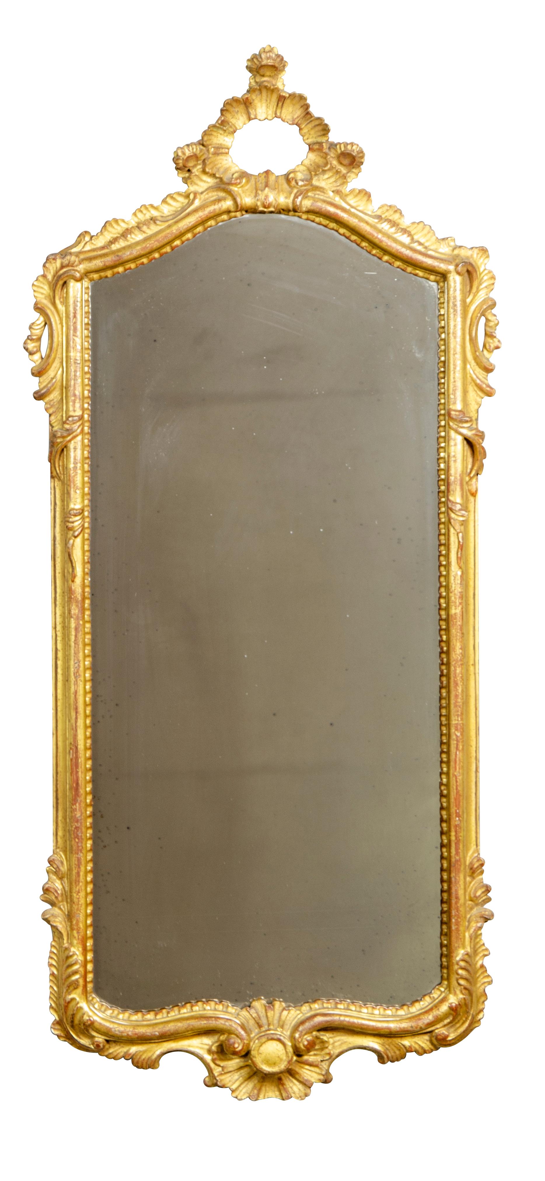 The arched mirror plate set in a conforming frame with a rococo frame with carved details.