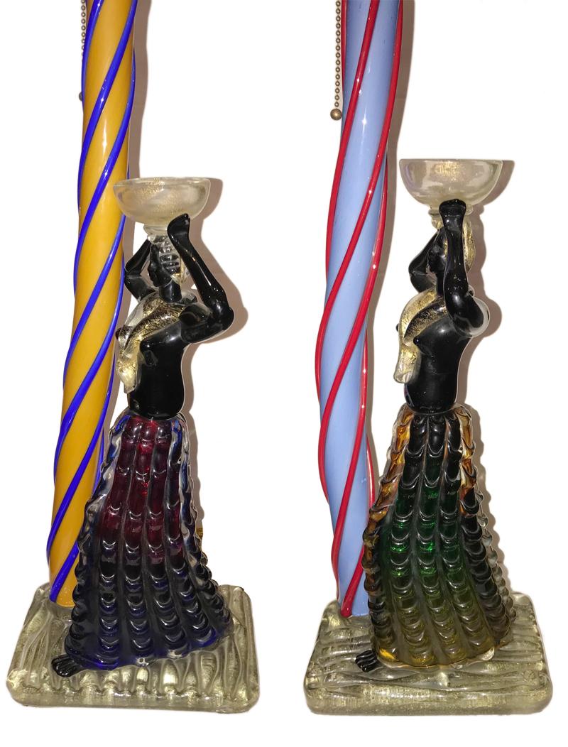 A very unique pair of circa 1940's Italian hand-blown figural art glass table lamps in the form of Carnival characters standing next to Venetian columns.

Measurements:
Height of body 21