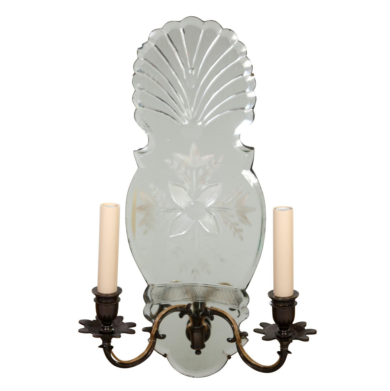 A pair of Venetian mirrored back, shell form, double arm sconces.  The shaped mirrored back vintage wall lights have a  cut glass design with a floral motif at the center, shell design at the top and two brass curved arms at the base.  A lovely