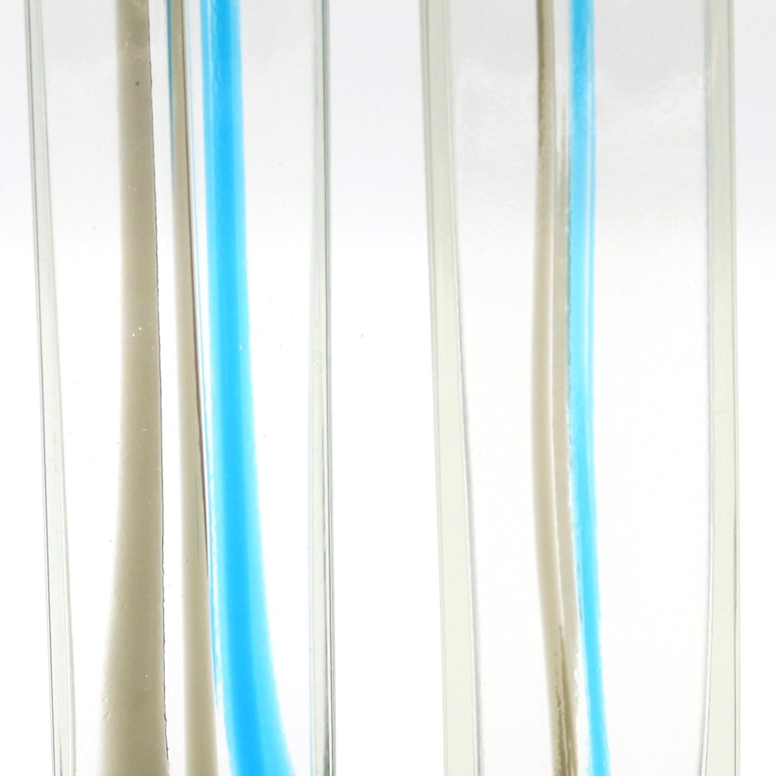 Coppia di vasi in vetro artistico italiano di Venini. Vetro trasparente con nastri fusi di colore grigio e azzurro. Inciso sul bordo: Venini Italia, con etichetta originale del produttore.
Dimensioni:
1) H:13¾ W:2¾ D:2¾.
2) H. H. 11¾ L. 2¾ P. 2¾