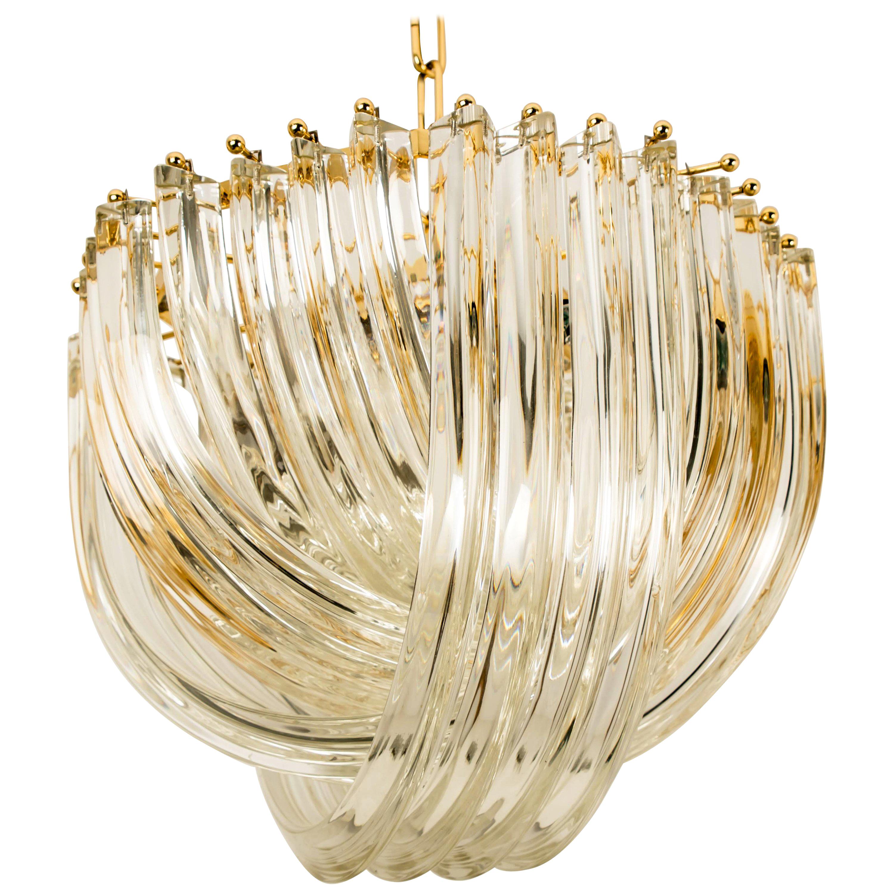 A impressive pair of light fixtures by Venini, Italy. Manufactured in circa 1970 (late 1960s and early 1970s). A handmade and high quality piece. Large curved crystal Murano glasses in different length mounted on a gold-plated brass frame. The