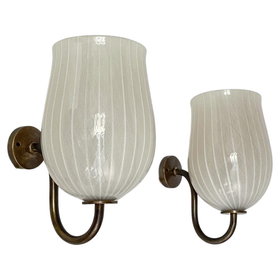 A pair of incredibly well-crafted Venini sconces in ‚zanfirico’ or ‚filigrana’ glass, hand-crafted in Murano in the 1950s. 

Made of solid brass with a dark patina, cream white hand-shaped Murano glass. 

This cane pattern of the ‚Zanfirico‘