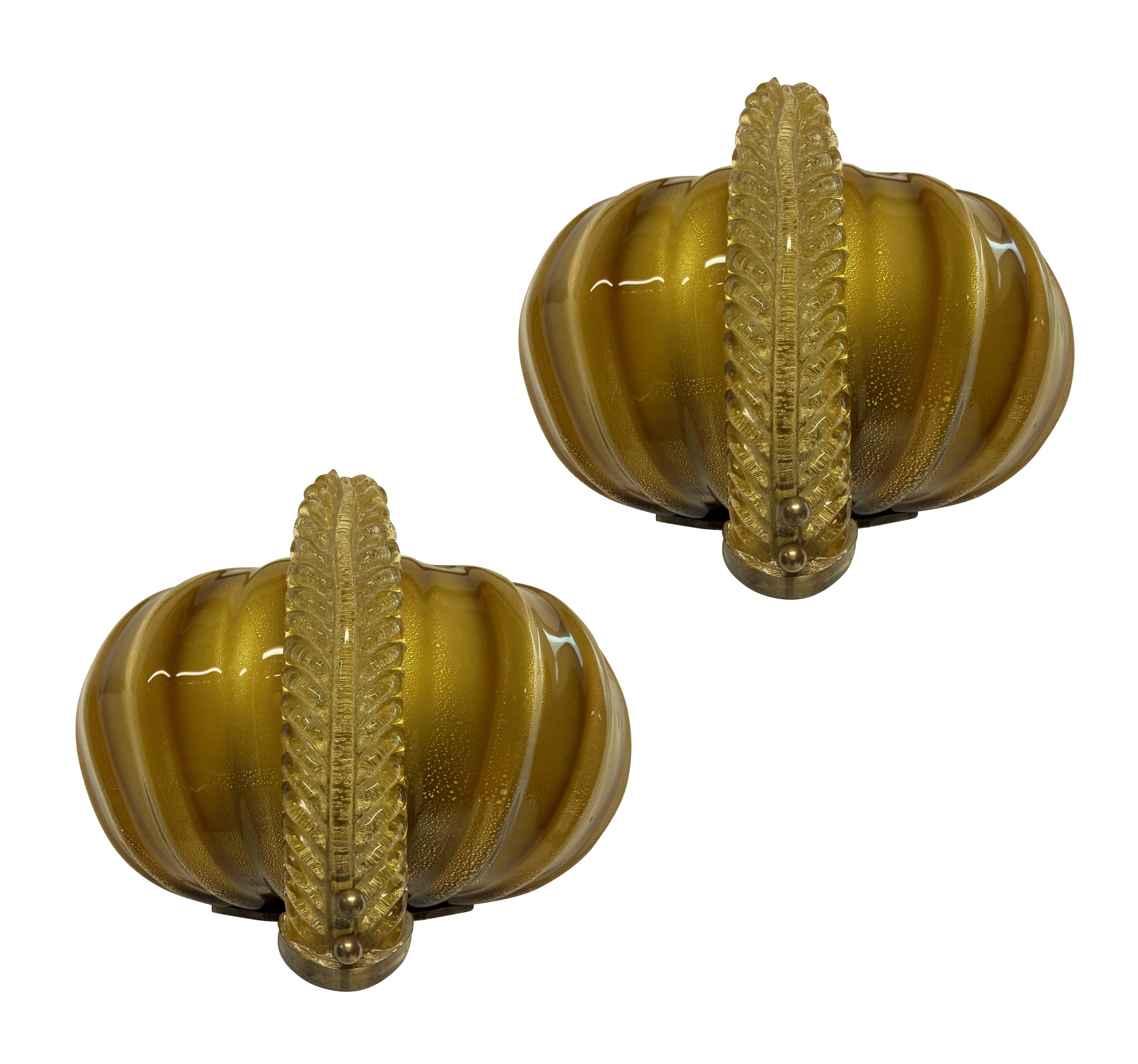A pair of good quality Venini wall lights in hand blown gold tinted glass with brass fittings in the form of feathered turbans. En suite with another pair.
