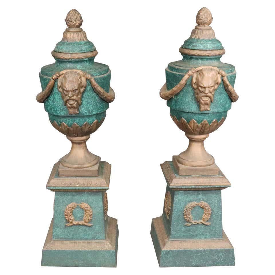 Pair of painted verdigris cast iron garden urns with bearded face and garland motif.