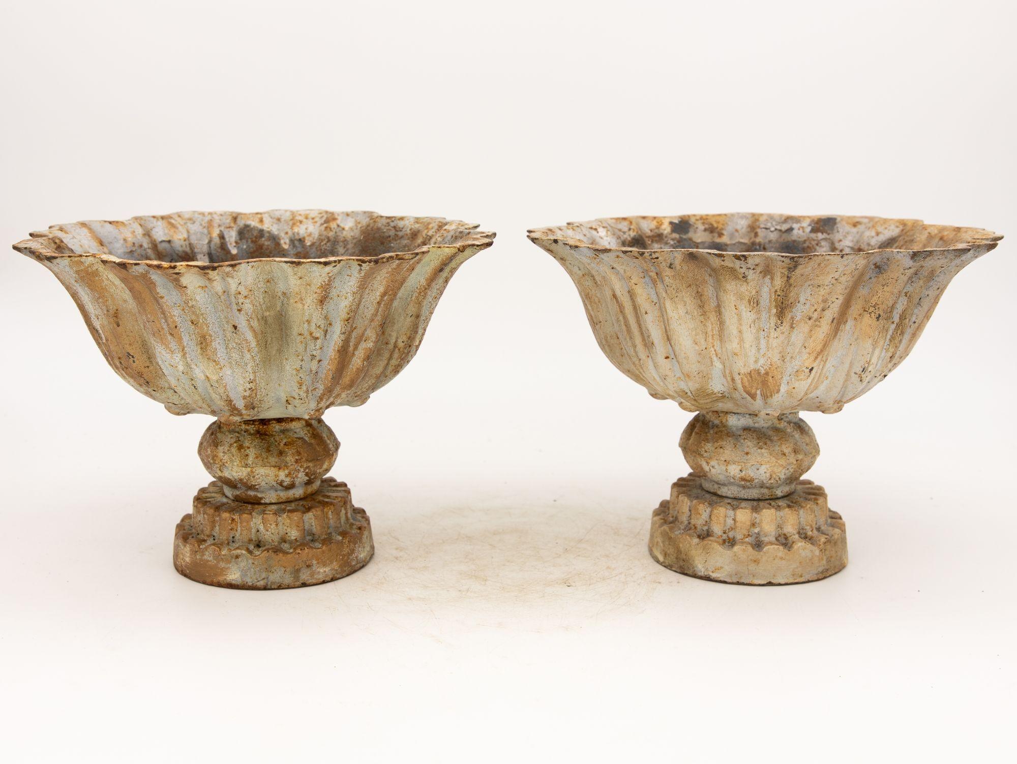 This captivating pair of late 20th-century iron tazzas exhibits a distinct verdigris patina, imbuing them with an aura of antiquity. Meticulously crafted, their wide, shallow bowls perch atop pedestals. The rich green-blue hue, a result of painted