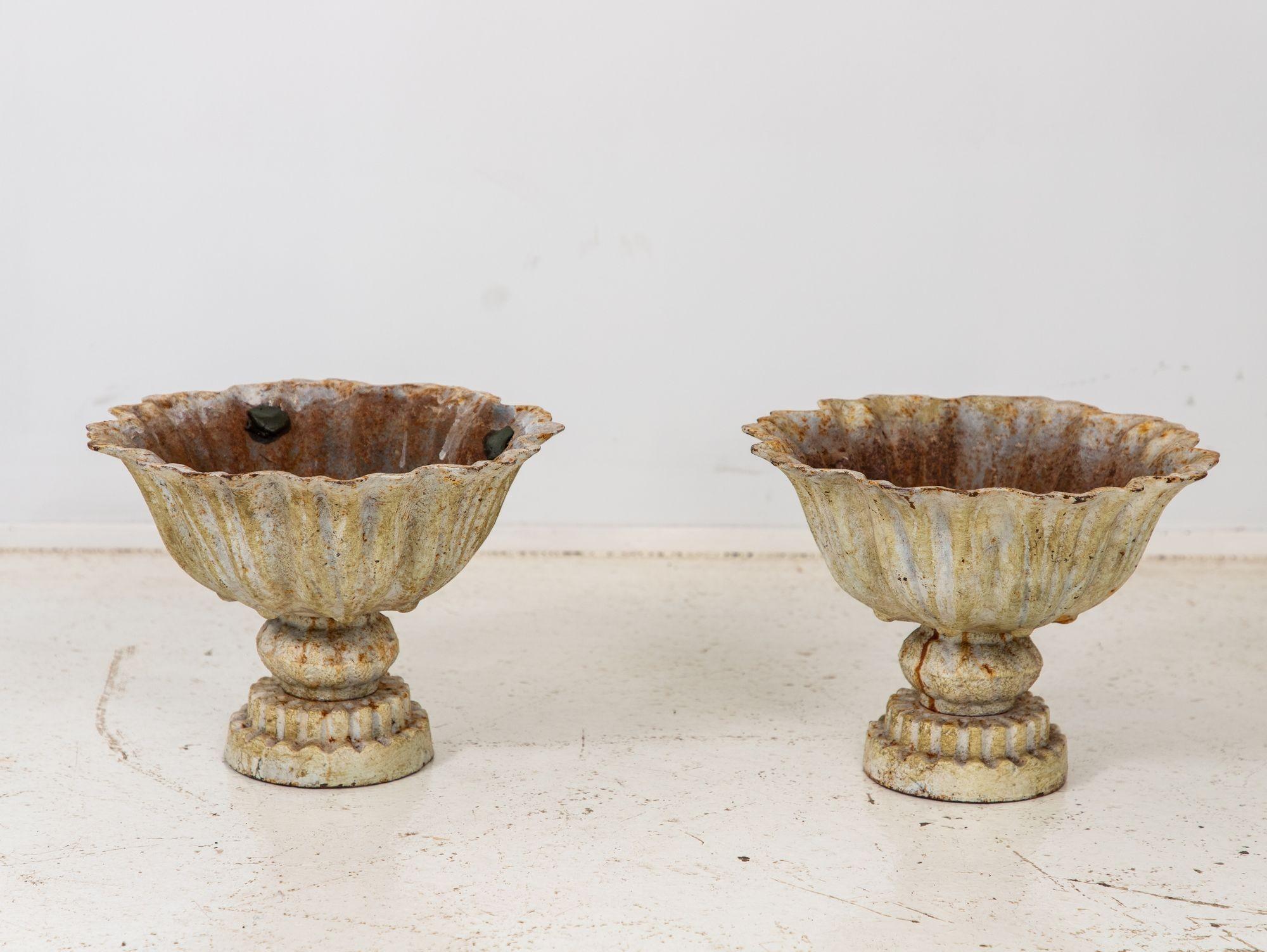 This captivating pair of late 20th-century iron tazzas exhibits a distinct verdigris patina, imbuing them with an aura of antiquity. Meticulously crafted, their wide, shallow bowls perch atop pedestals. The rich green-blue hue, a result of painted