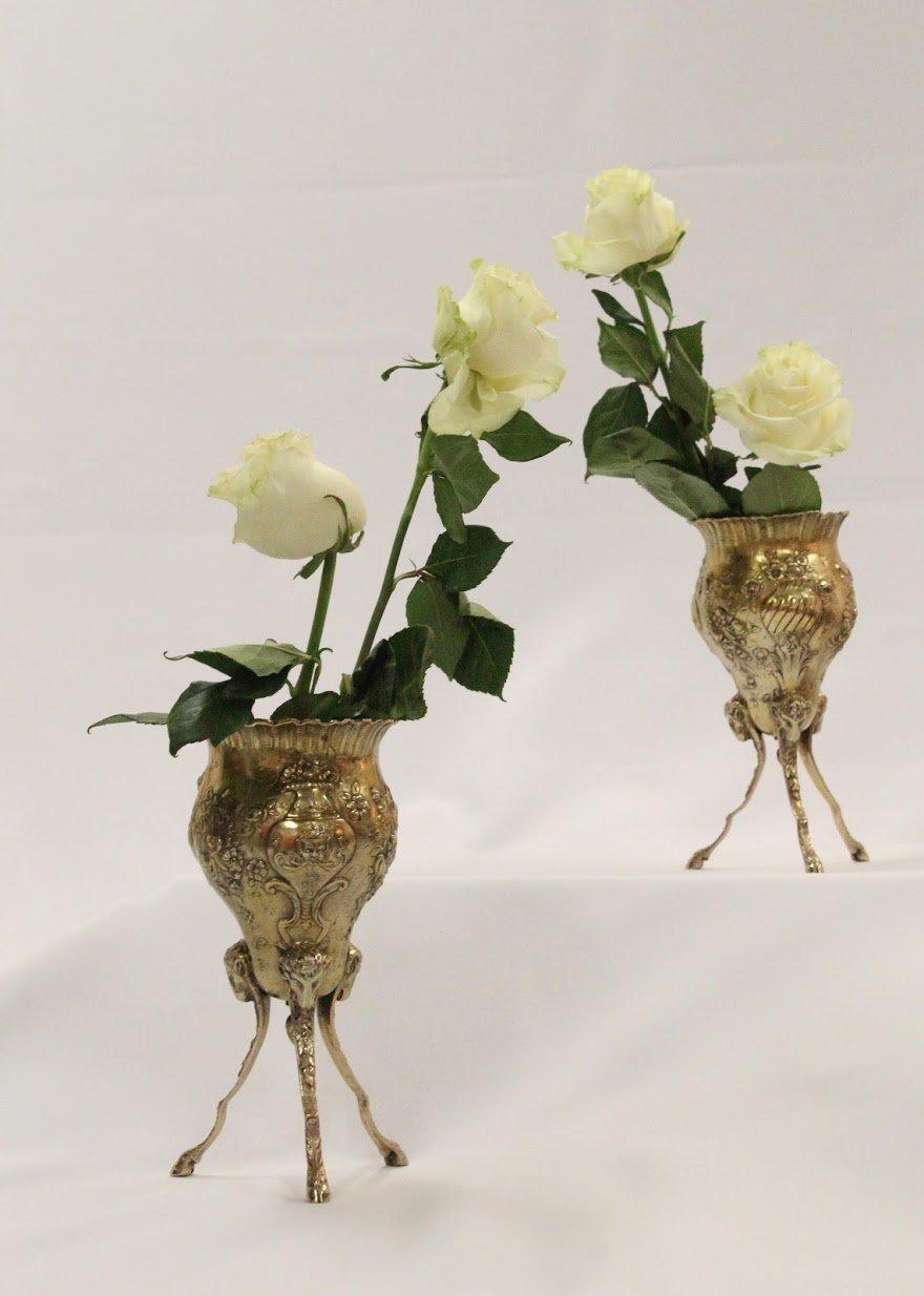 Pair of German continental silver and vermeil vases with gorgeous bows and flowers decorating the surface, three tri-dimensional ram heads by each leg, hooved feet. Measuring approximately 9 inches tall and 4 1/3 inches in diameter at top. Weighing