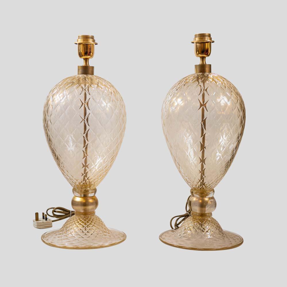 These exquisite table lamps are a pair of blown Murano glass Veronese lamps. They are crafted using clear glass with luxurious gold inclusions, creating a rich and opulent look. The glass surface is meticulously hand-worked to create beautiful
