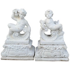 Coppia di statue vintage in pietra fusa di putti reclinati su piedistallo