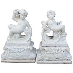 Paire de statues de Putti couchées en pierre moulée sur piédestal