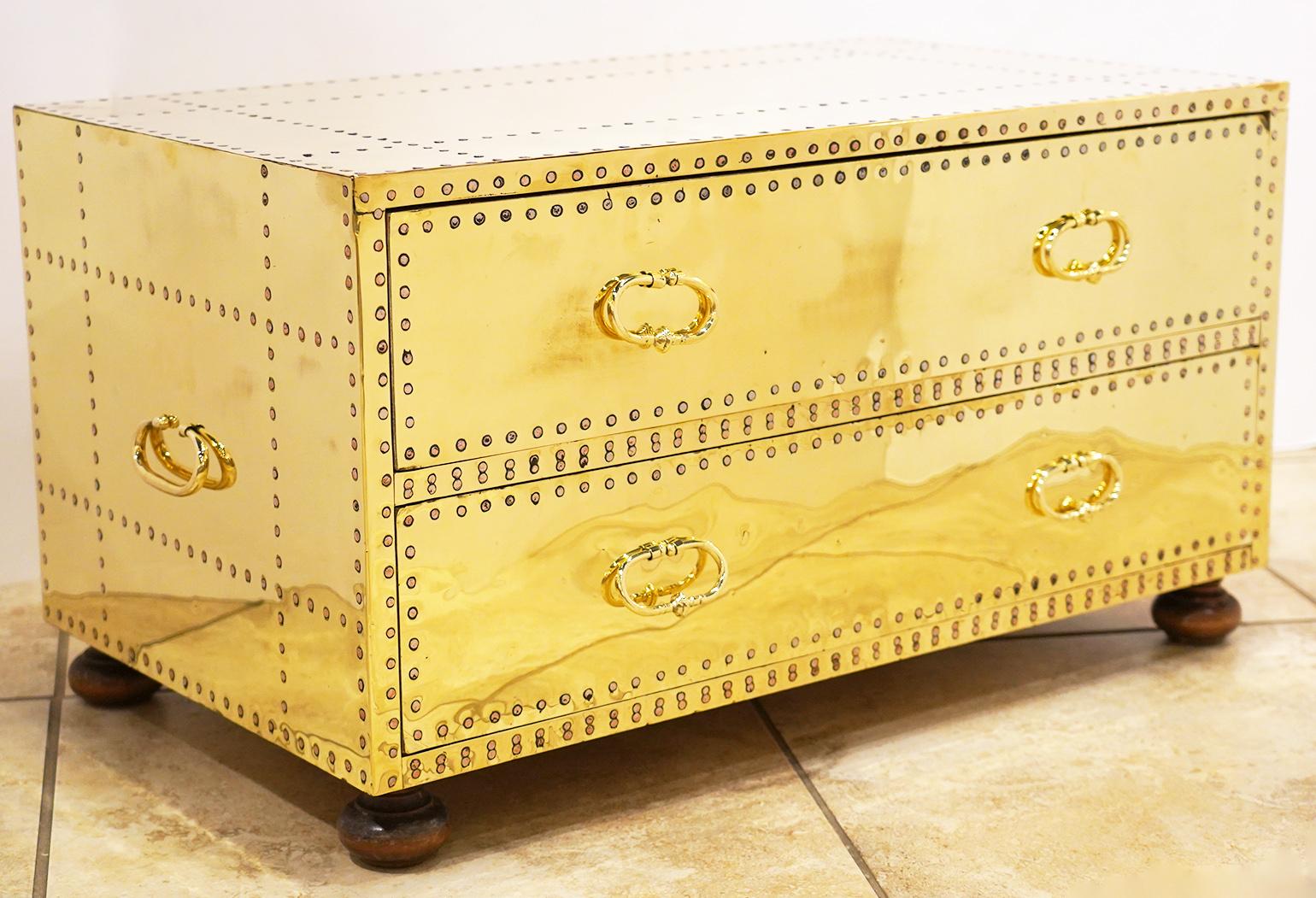 A pair of spectacular polished brass clad and copper nail studded 2-drawer chest on turned wood feet by Sarreid, Ltd. The chests have been recently professionally polished and clear coated. Made in Spain in the 1970s and in excellent condition.