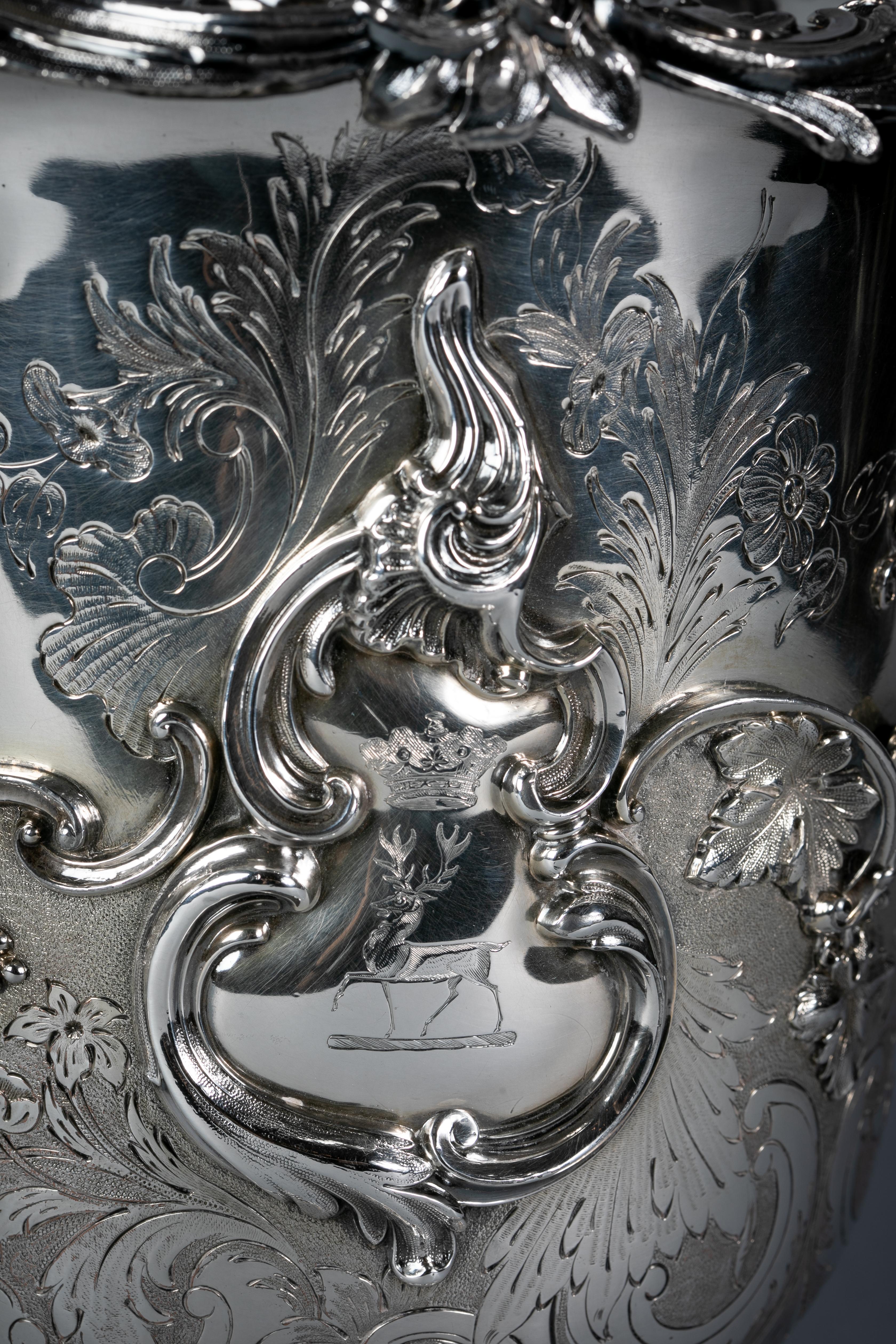Boldly chased, engraved and applied with grape and vine decoration with the crests on either sides framed within a double-scrolled cartouche in high relief. The base with further scroll, leaf and floral decoration. The rim similarly decorated in