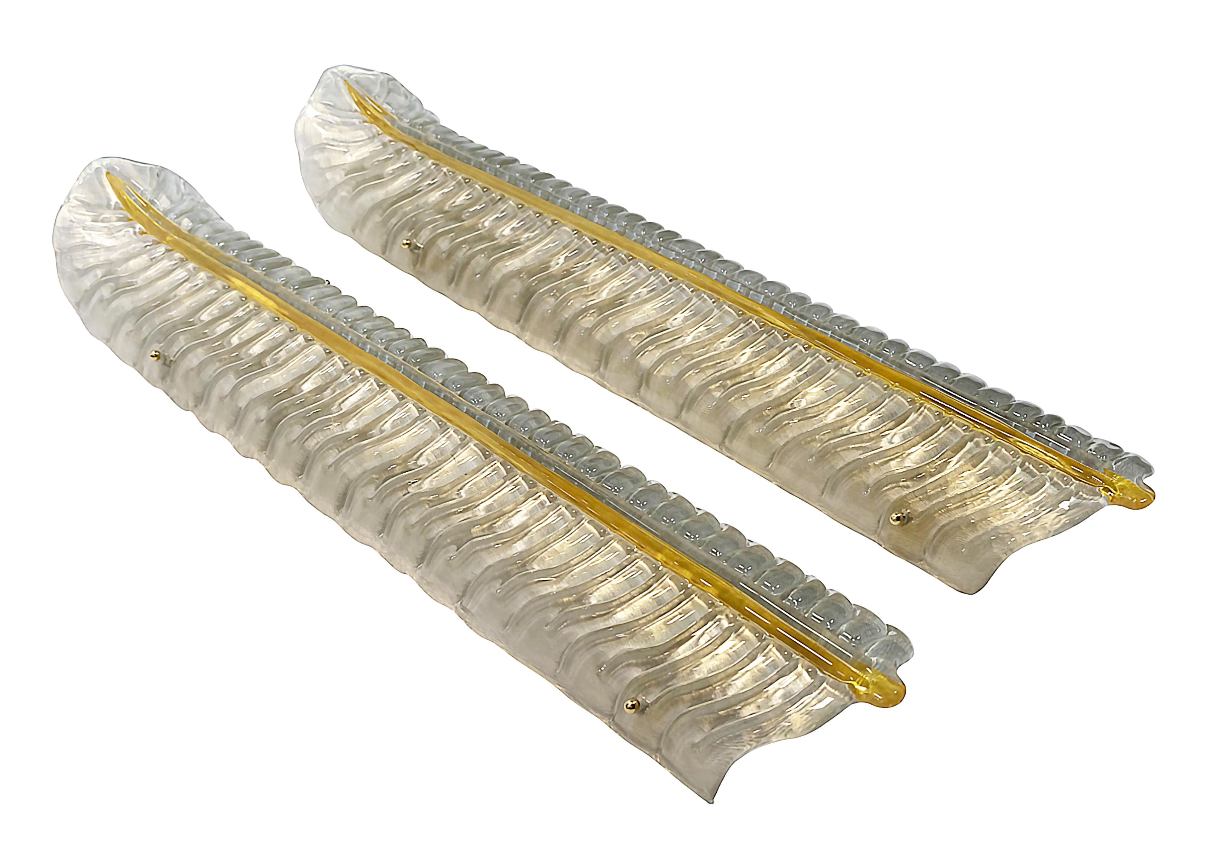 Paire de très grandes appliques murales italiennes en verre de Murano fait main en forme de feuille et base en laiton. Le verre de Murano est de couleur ivoire/gris clair avec un décor de verre à rayures jaunes incrusté. 
Chaque applique est équipée