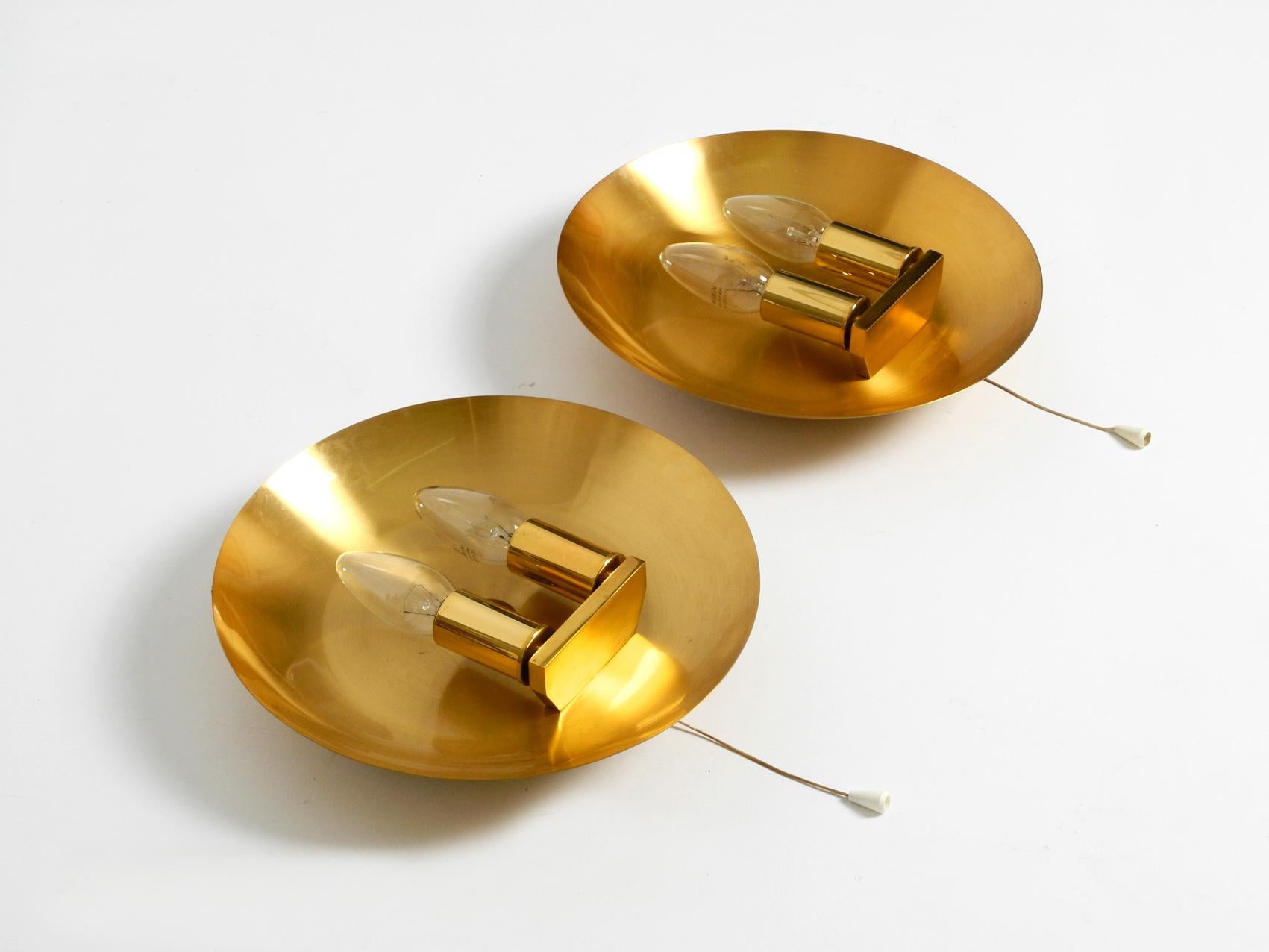 Pair of very rare and high quality 1970s round brass sconces by WKR. Beautiful minimalistic design. Made in Germany.
Entire brass lamp with two E14 original plastic sockets each with a brass sleeve. The shade is arched and looks like a plate.
