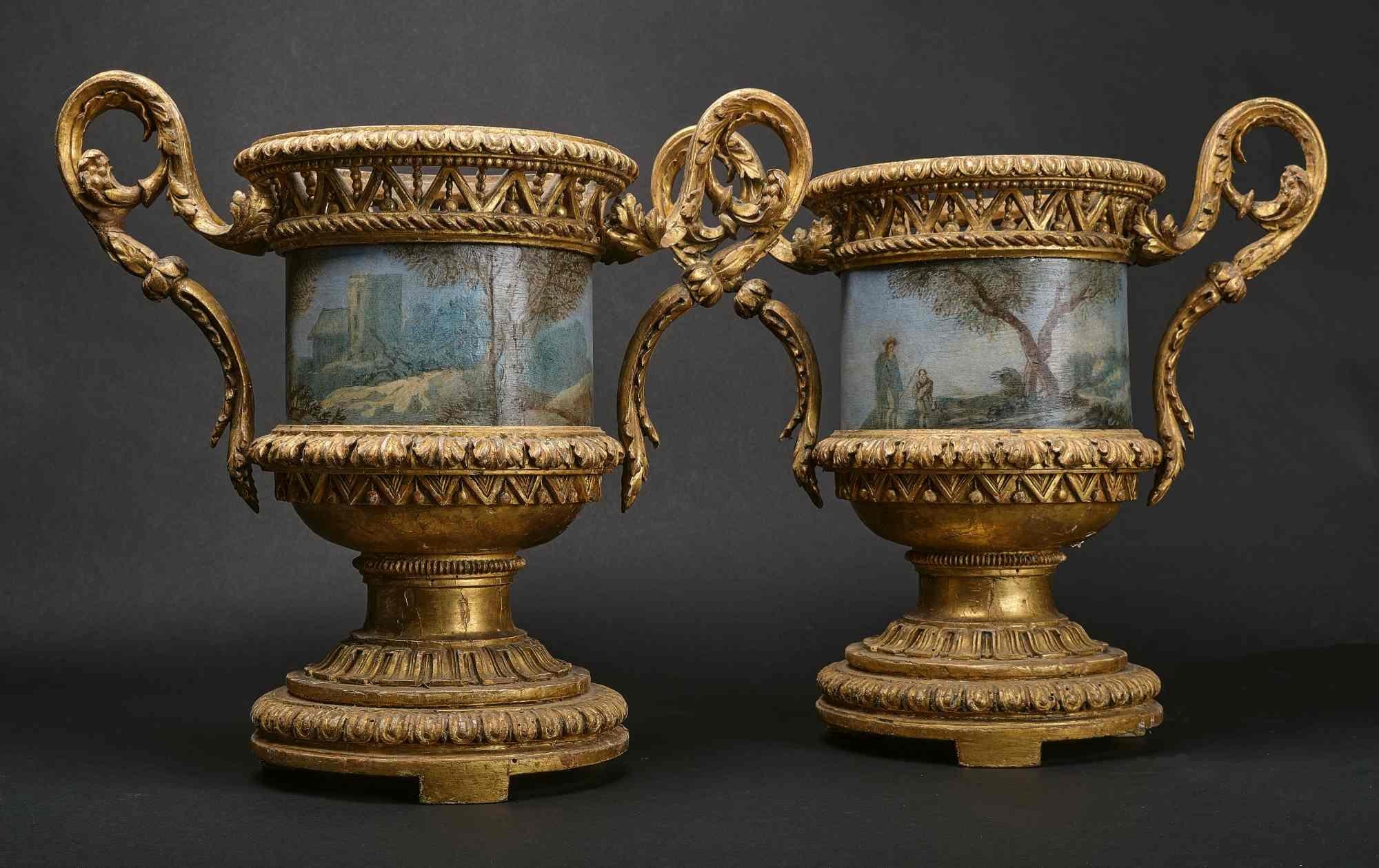 Cette paire de vases romains de la période Louis-XVI est extrêmement rare. La virtuosité de la sculpture suit avec tous les éléments le style Louis XVI. La dorure n'est jamais touchée. Les pots de fleurs en tôle peinte sont décorés de paysages